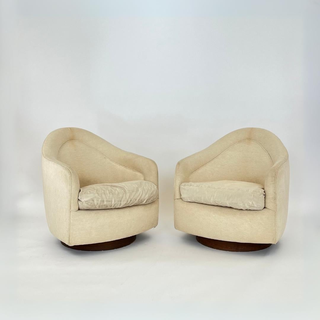 Pair of Milo Baughman for Thayer Coggin teardrop swivel chairs with Walnut plinth bases.  In all original condition, with wear/staining to upholstery and minor losses to plinth base; reupholstery and base refinishing are recommended on both.
29ʺW ×
