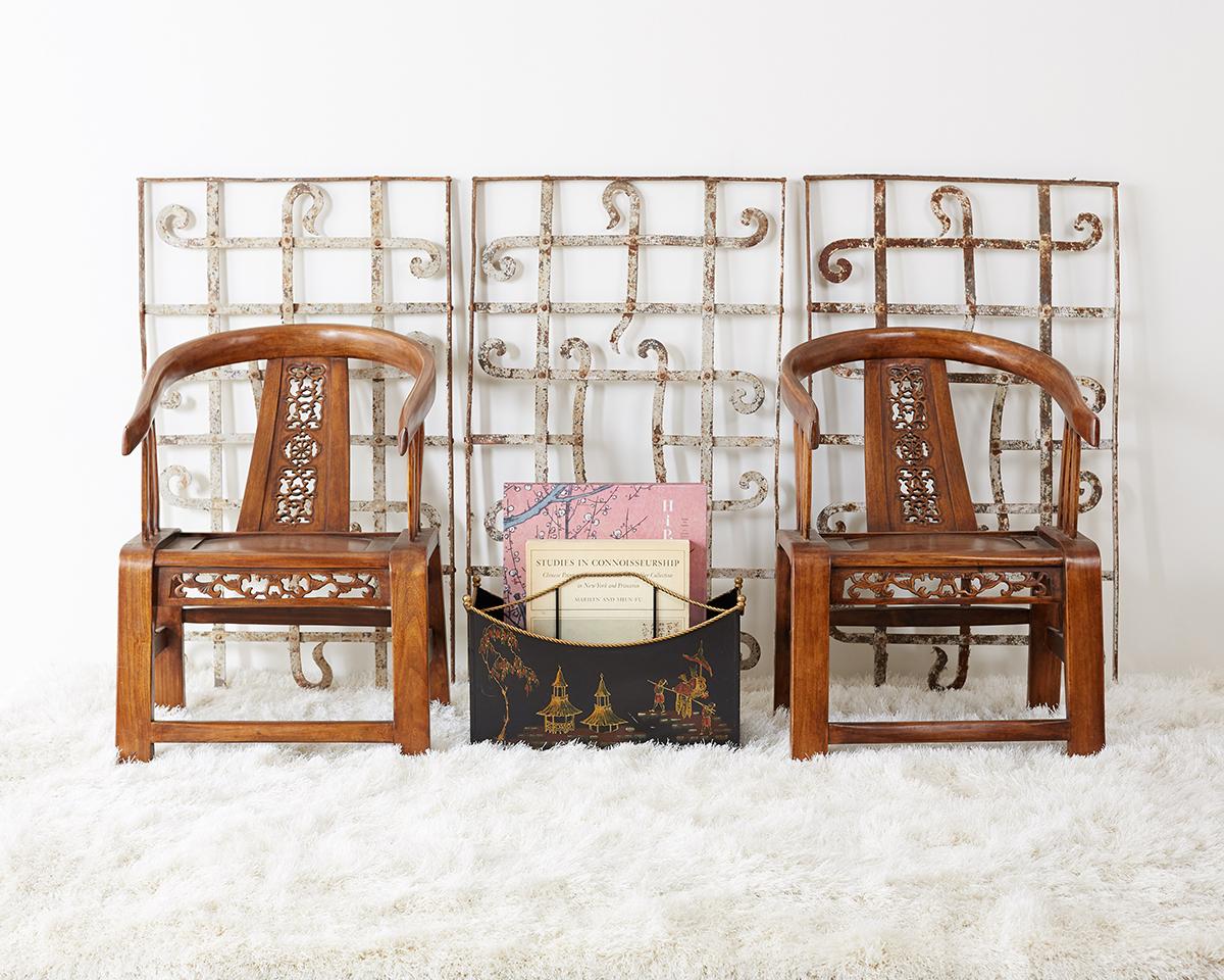 Stylish pair of Chinese Ming dynasty style horseshoe chairs constructed from elm. Each horseshoe shaped arm rail is supported by an intricately pierced splat and apron. The arms have three supports on each side giving the chairs a unique profile.