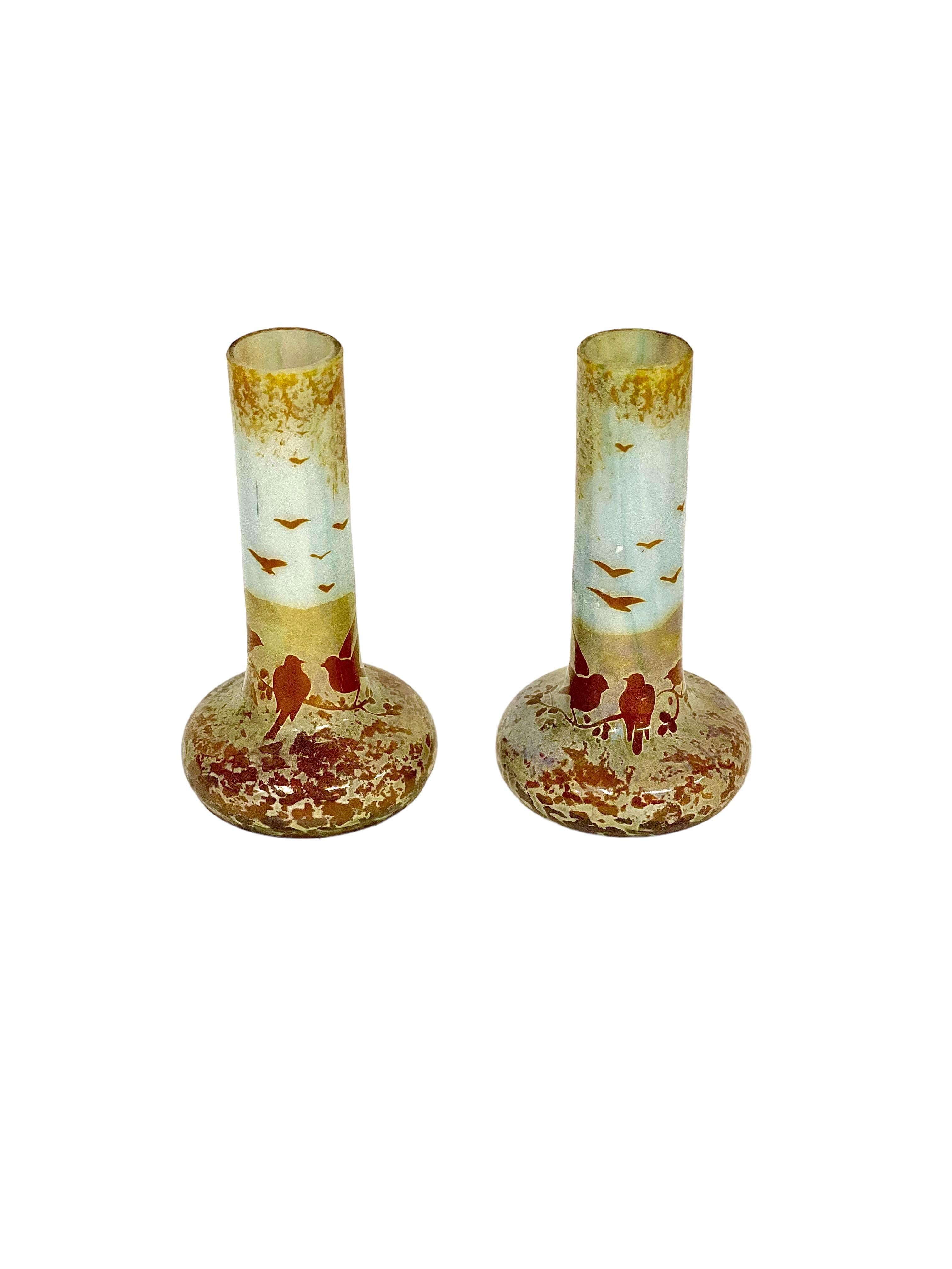 A charming and diminutive pair of soliflores, or stem vases, in muted shades of white, gold and terracotta, depicting a gathering of birds on a branch, and in the sky. These tiny tubular vases, designed to each hold a single bloom, are created from