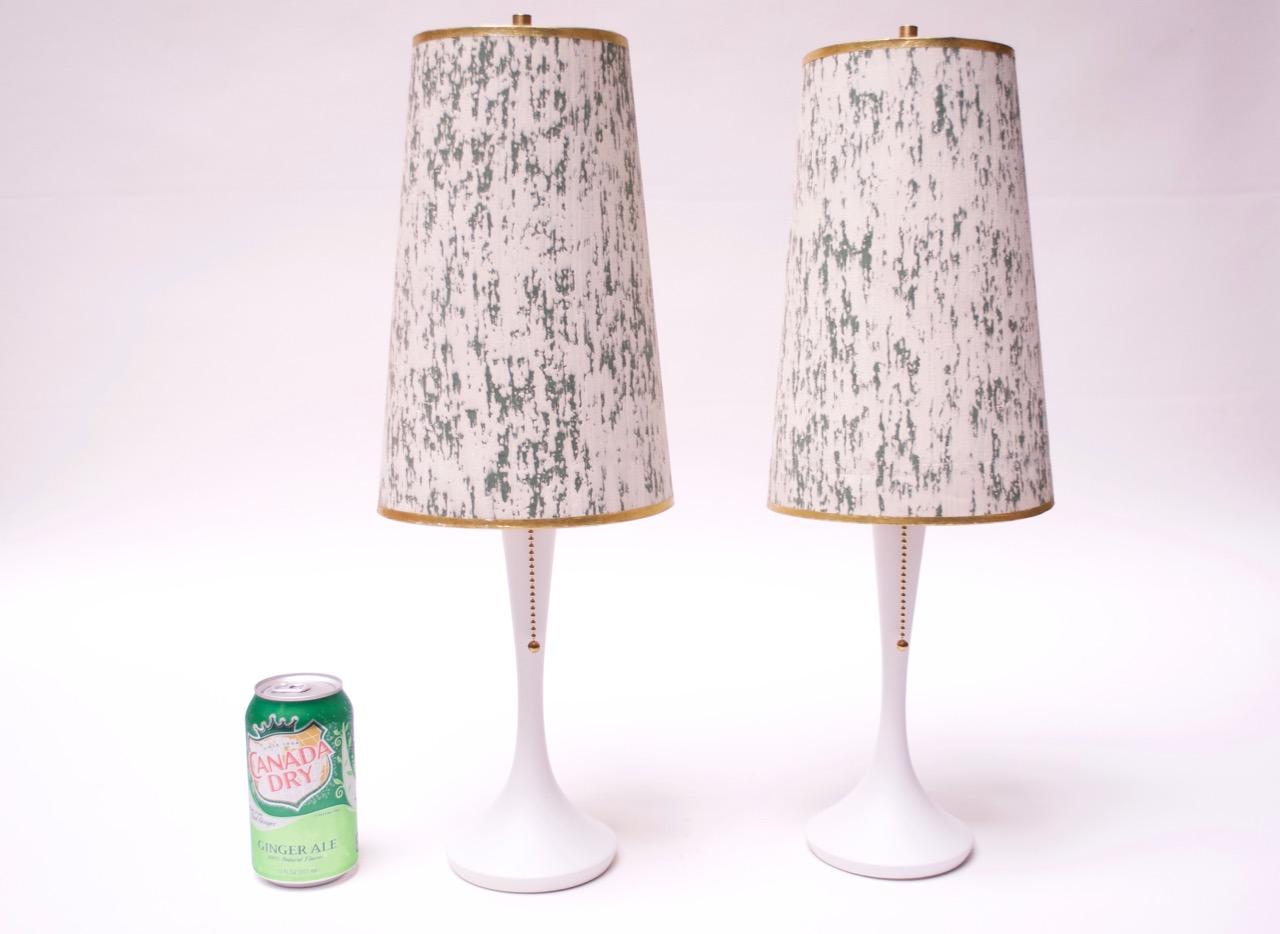 Pair of diminutive circa 1950s table lamps composed of simple, painted white wooden bases paired with off-white and green paper shades with gold trim. Lamps have been newly restored (socket and pull-chain are all new, as is the paint). The shades