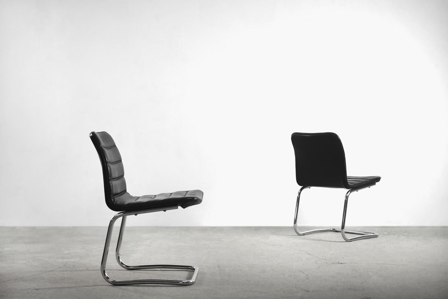 This set of two minimalist chairs was manufactured in Germany by Pol International during 1960s. The camber seats were upholstered in black leather with oblong seams. The minimalist base is made from chrome-plated steel. The finest quality made in