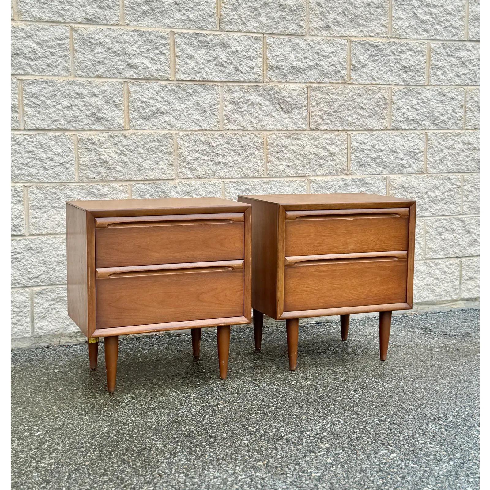 A pair of mid-century style nightstands featuring a sleek, minimalist design with Scandinavian influences. Built in the USA with durable craftsmanship, each piece offers ample storage through two roomy drawers. The facade is accented with finely
