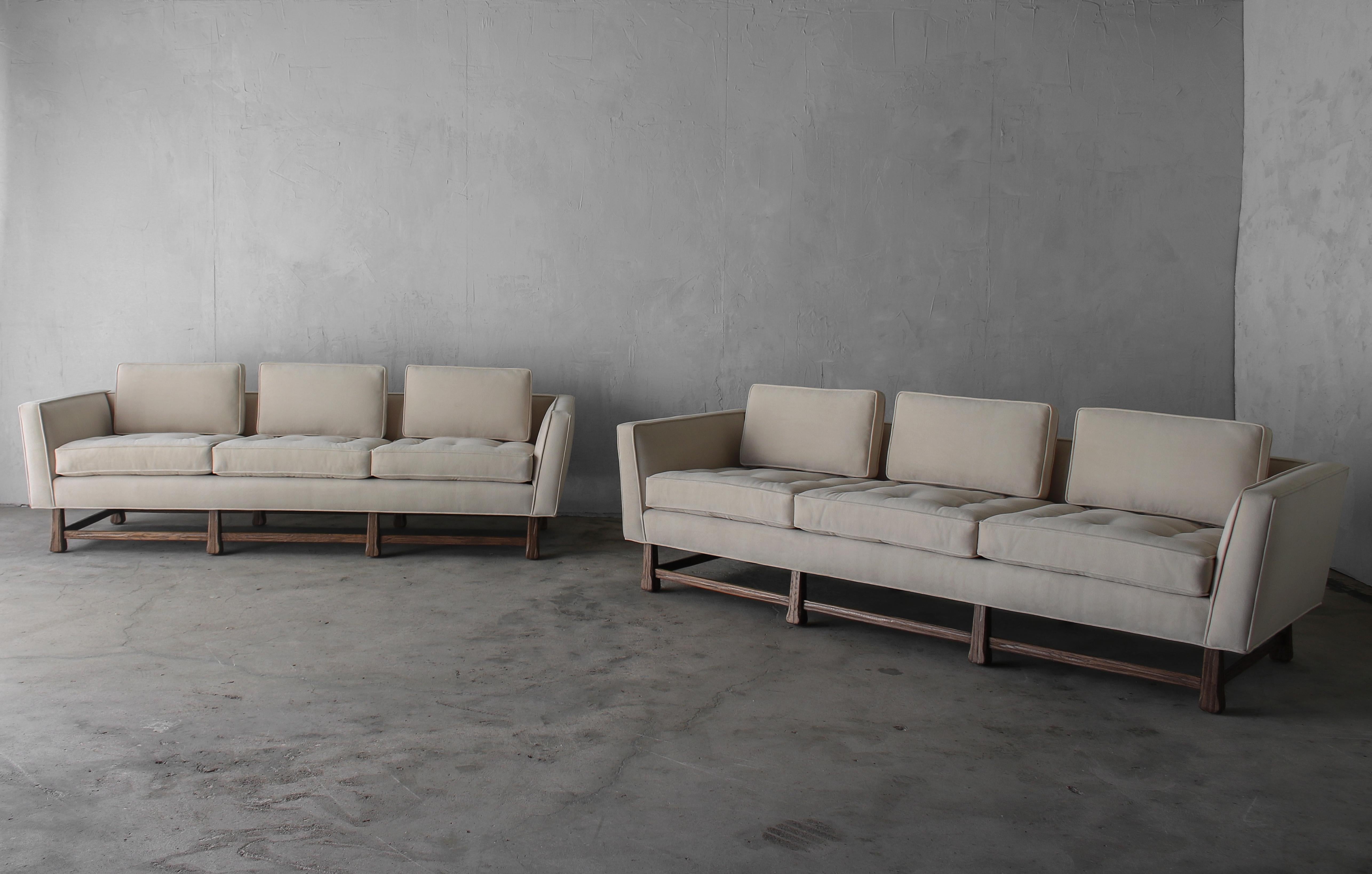 Absolutely stunning pair of midcentury sofas. The angled arms and beautiful sculpted oak bases give these beauties lots of character. They are a very minimalist appeal to them.

This is a substantial pair of vintage sofas in like new condition.