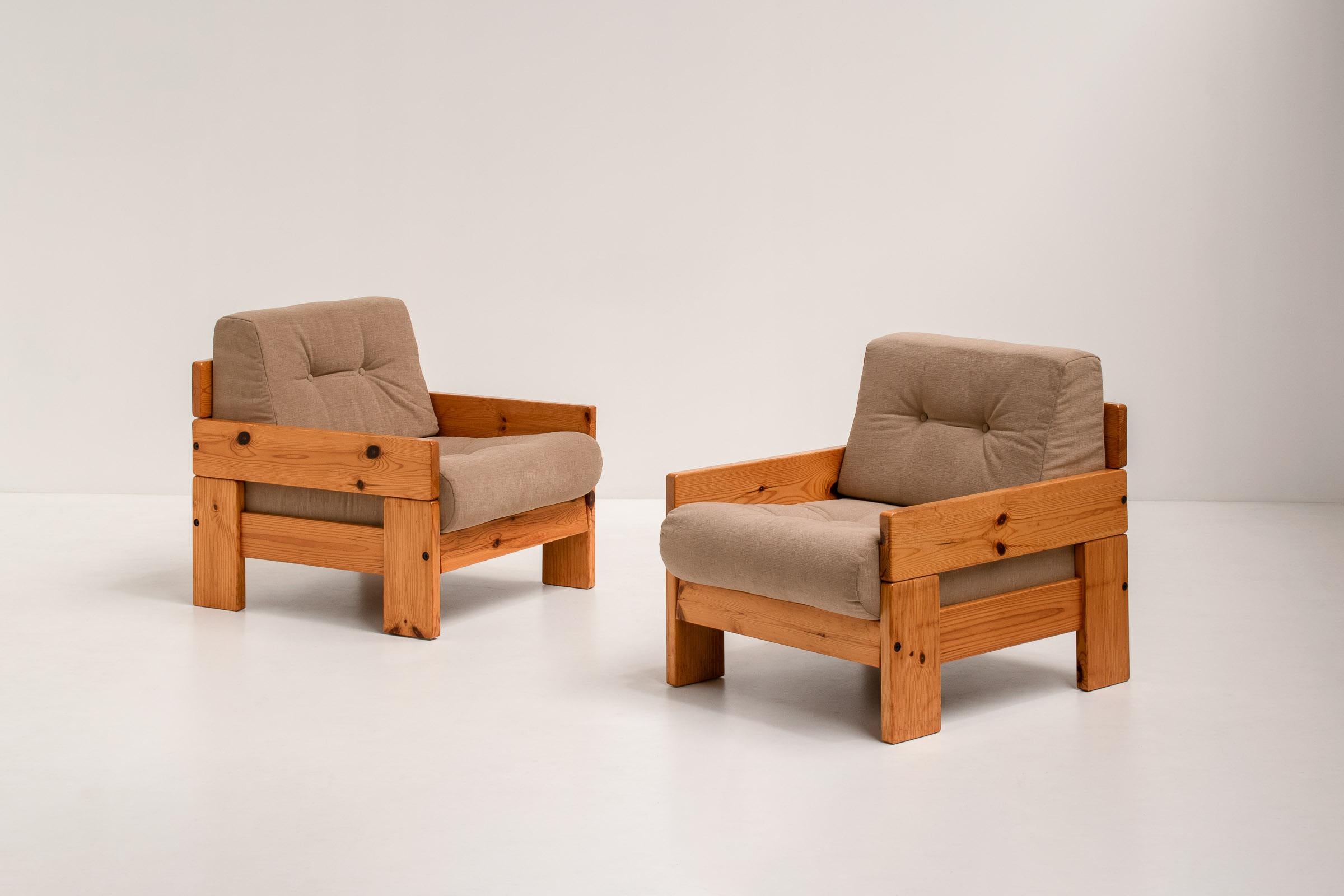 A pair of rare, minimalist lounge chairs made out of solid pine wood in Italy during the 1970s. 

These armchairs have chunky arms and a solid wooden frame made out of large slabs of wood. The wood has a beautiful golden shade that adds warmth to