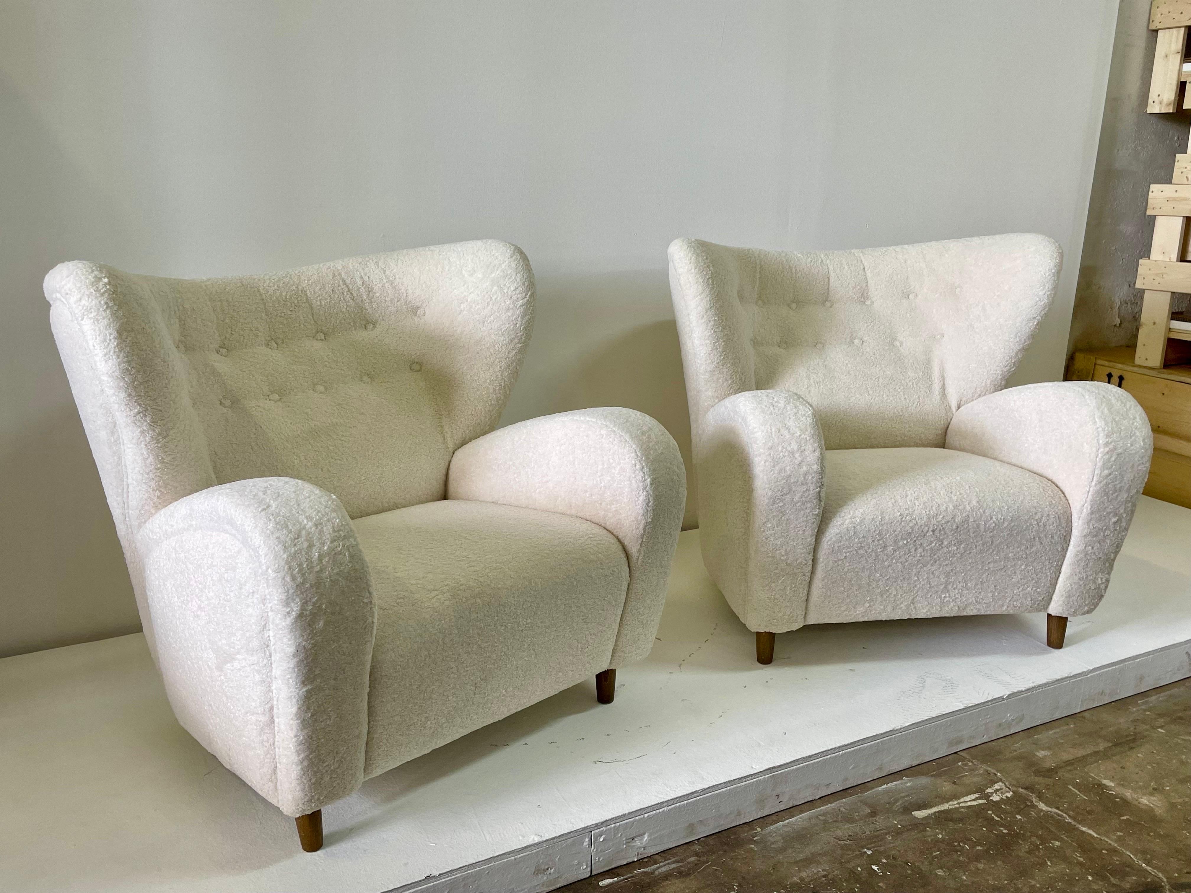 Poltrone moderne francesi in morbido e lussuoso tessuto boucle incontaminato.  Schienale a doppia fila di ciuffi con schienale alato oversize e piedini in legno.