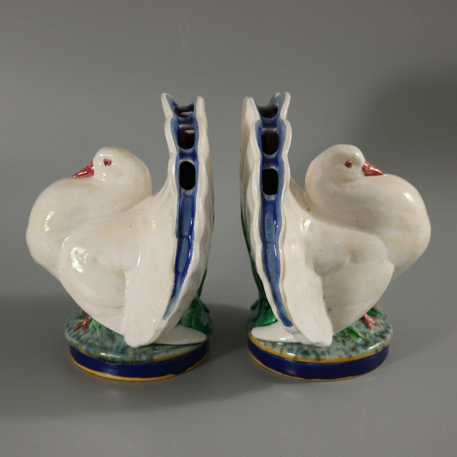 Pair of Minton Majolica flower holders which feature a fantail pigeon, standing on a leafy base. Flower inserts around the tail. Colouration: white, green, cobalt blue, are predominant. The piece bears maker's marks for the Minton pottery. Bears a