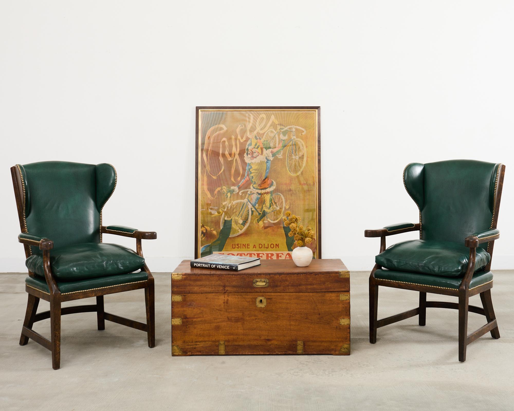 Étonnante paire de fauteuils de barbier à dossier en cuir, conçus dans le goût Regency anglais par Minton-Spidell, Los Angeles, CA. Les chaises sont dotées d'un large cadre en hêtre dont la finition sombre a été volontairement patinée afin d'imiter
