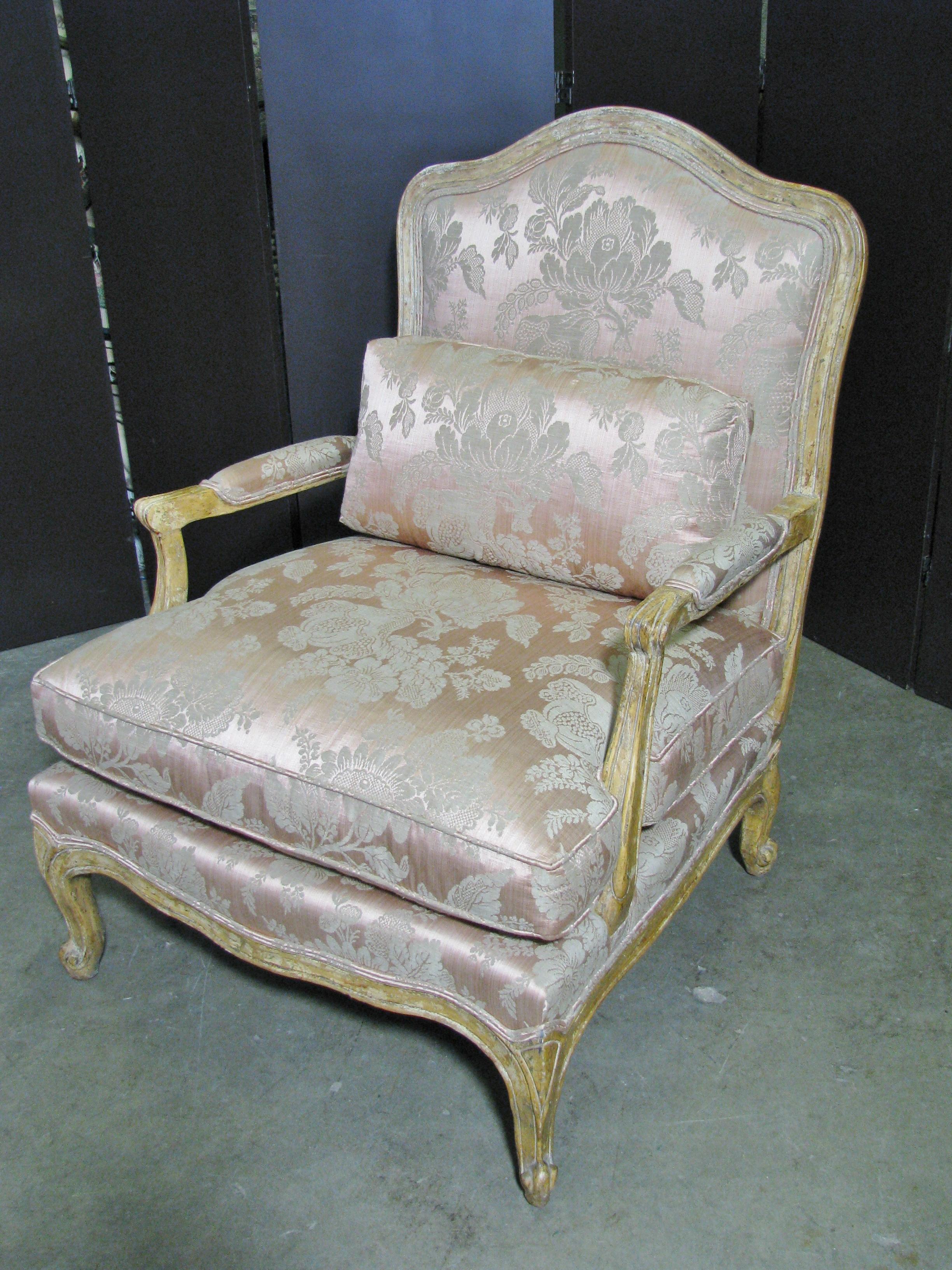 Stunning pair of French style armchairs by high-end custom furniture maker Minton-Spidell. Finished in a distressed, flaky ochre finish, with a convincing aged look. Intentional wear allow wood and a whisper of a blue-green color show through. The