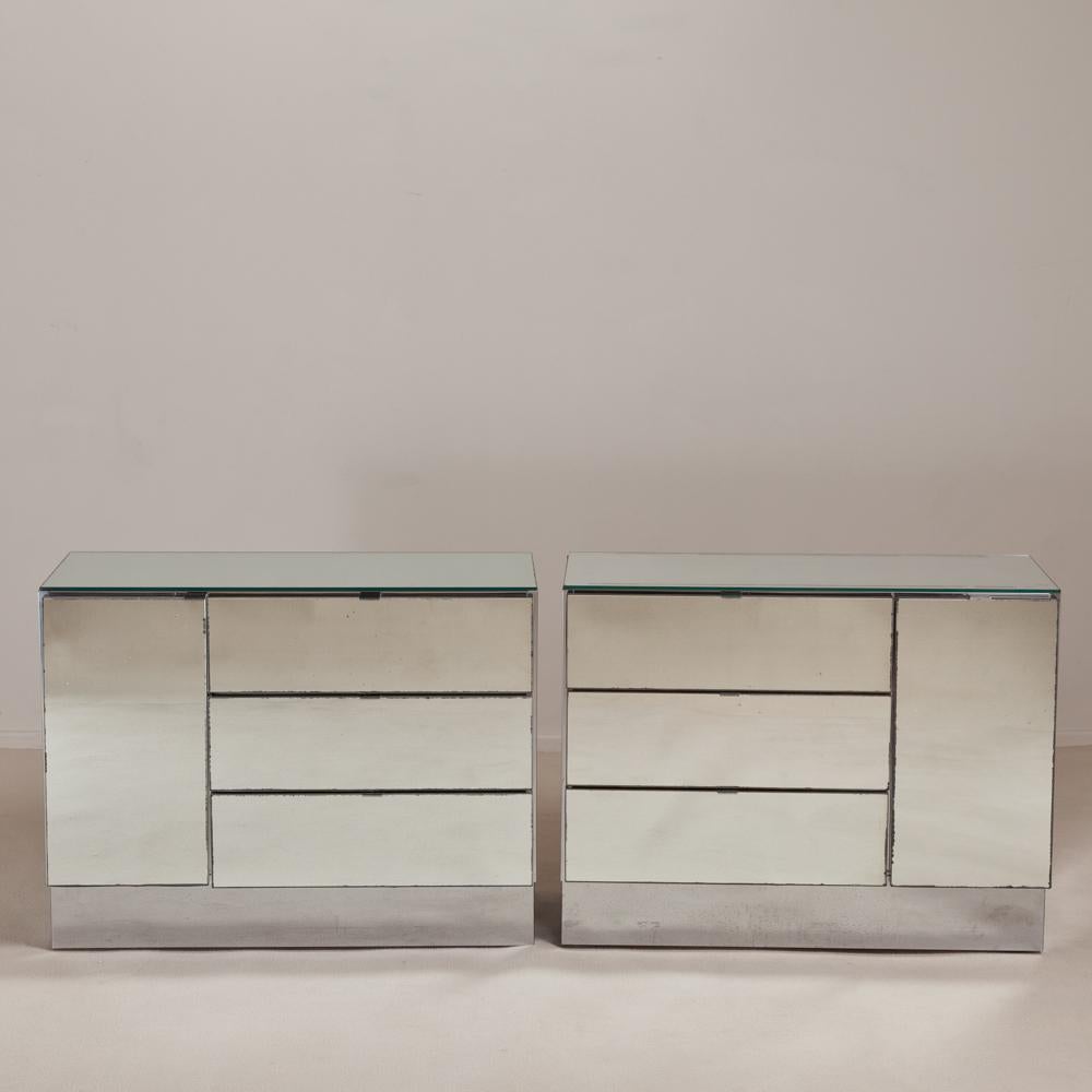 A large pair of handed mirrored and steel wrapped side cabinets with three drawers and a single door, by Ello, USA, 1960s.