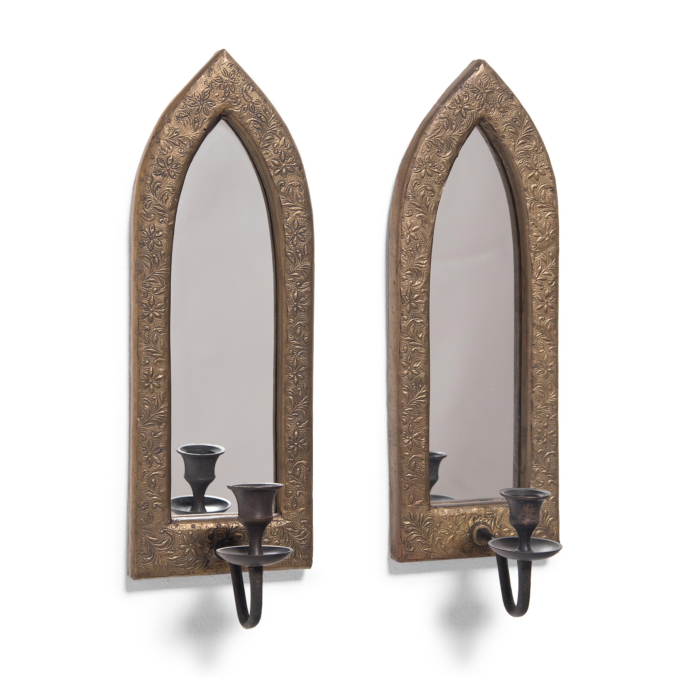 This pair of wall mounted candle sconces are designed in the style of the English Arts & Crafts movement and feature mirrored backings enclosed by arched frames. Shaped like Gothic lancet windows, the frames are made of wood with an outer layer of