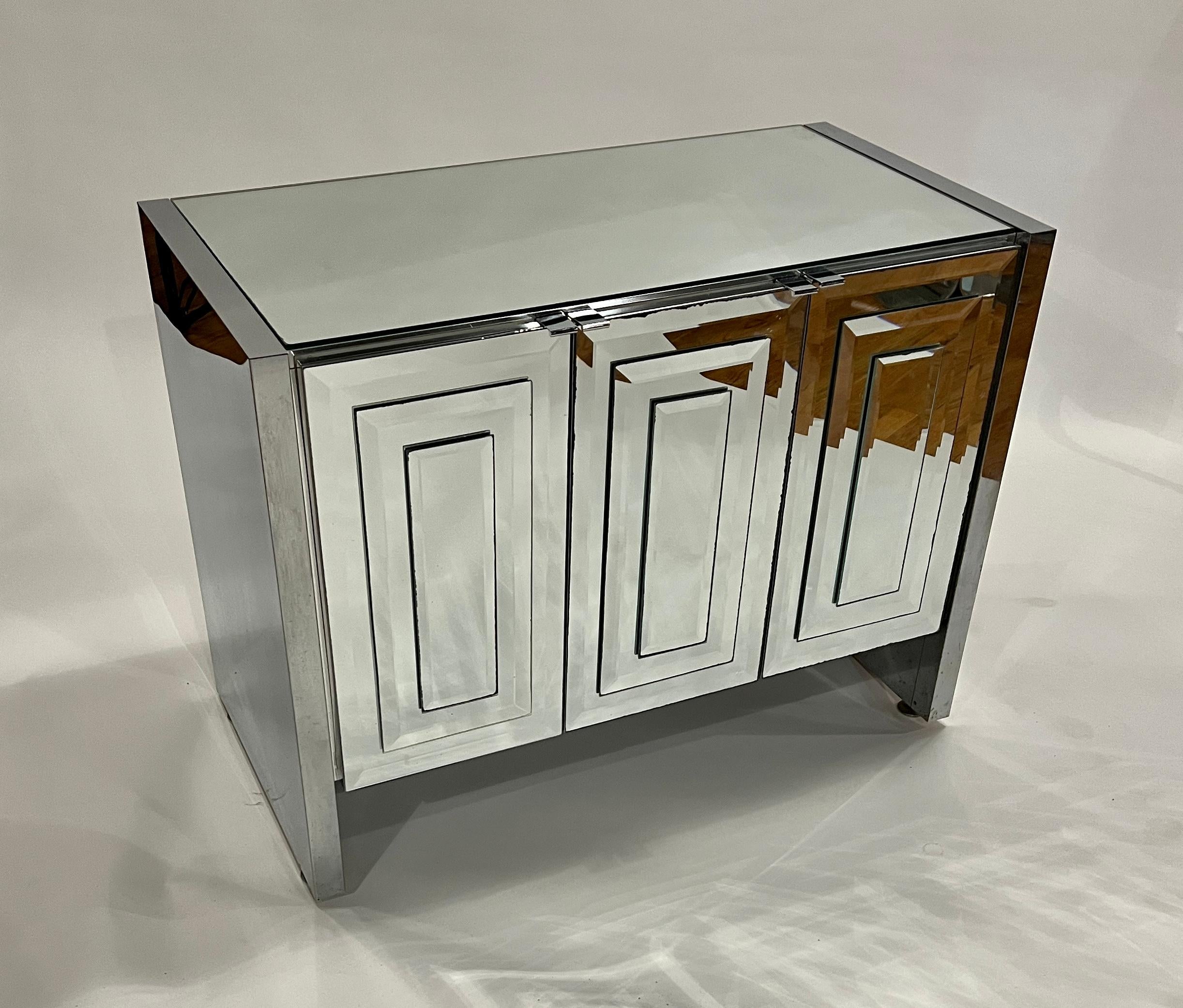 Pair of mirrored chest of drawers by Ello Furniture, Italy 1960s. Each cabinet is made of three beveled mirrored paneled hinged cabinet doors revealing three interior pullout drawers in lacquered white wood and chrome pulls. 
These large chests can