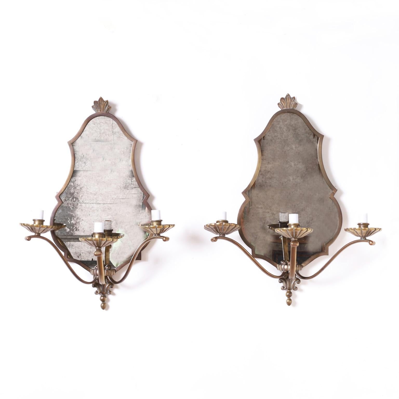 In vogue pair of three arm brass sconces with classic French form having early art deco influences and replaced distressed mirrors. Signed Jansen on the wooden back.