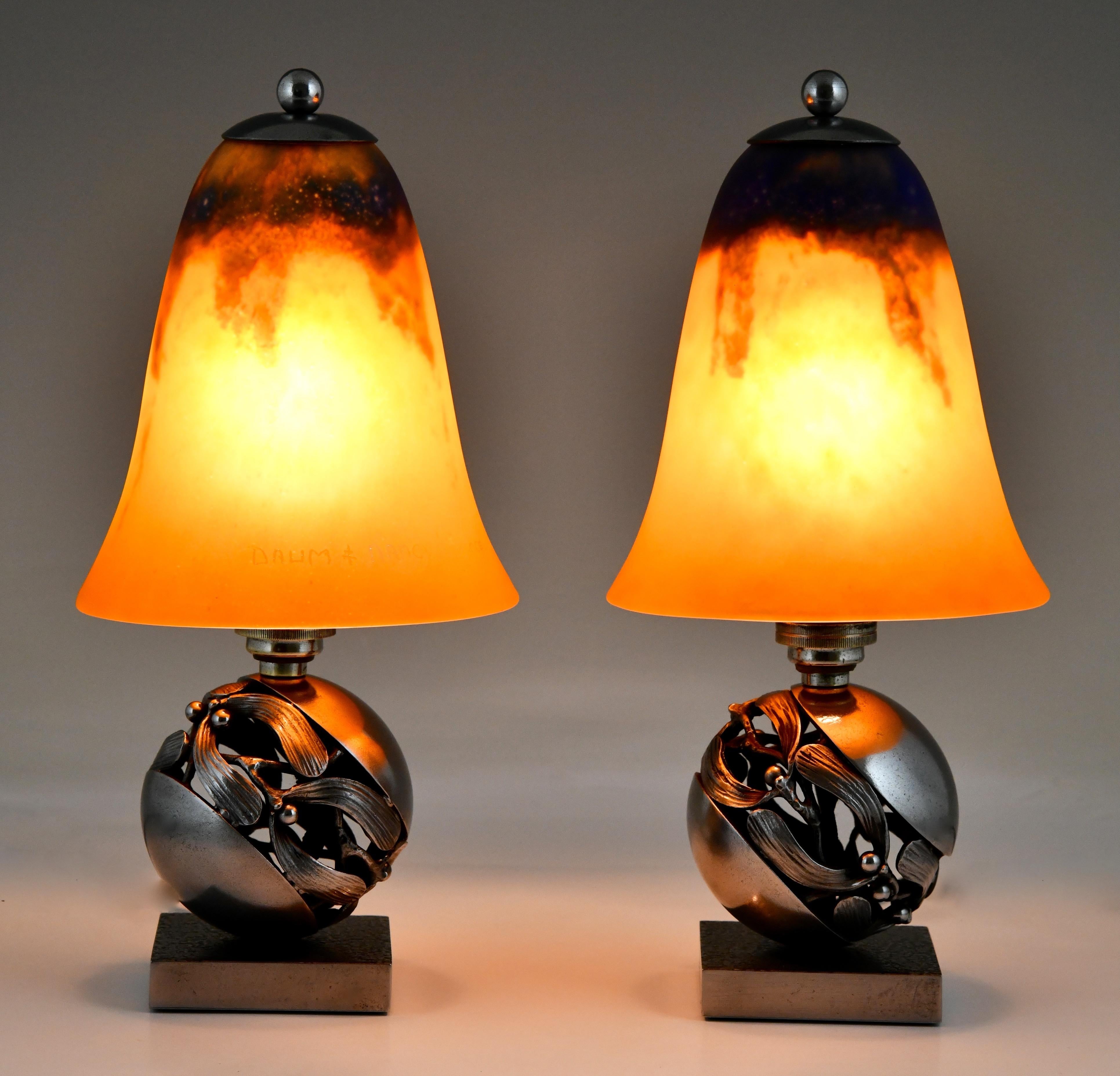 Pair of Mistletoe or Boule de Gui Art Deco table lamps by Edgar Brandt and Daum. 
Wrought iron lamp bases stamped E. Brandt.
Orange and bleu pâte de verre glass shades signed Daum Nancy. 
France 1925.
This model -as paperweight- is illustrated on