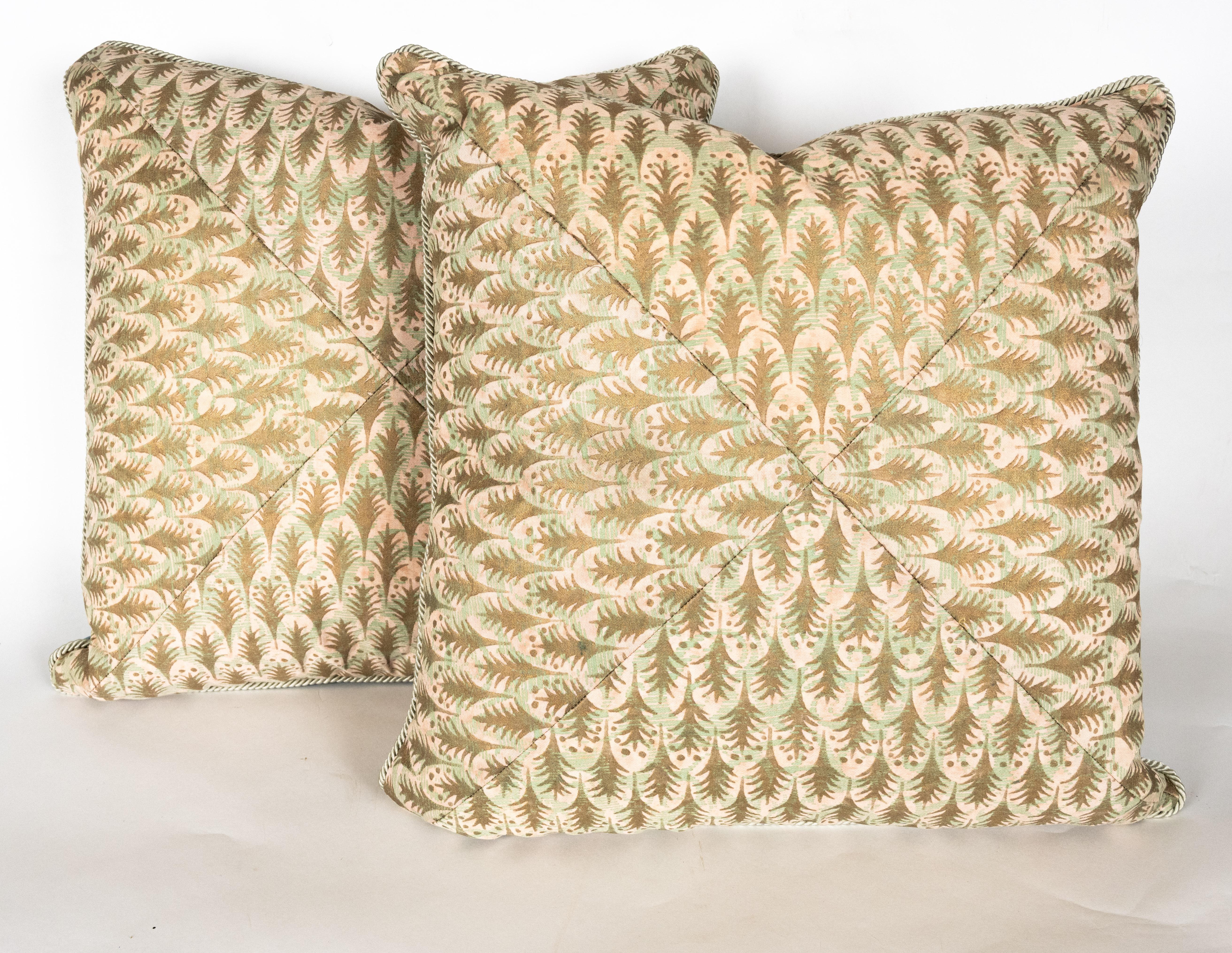 A pair of Fortuny fabric mitered cushions in the Puimette pattern, shell pink, powder blue, and gold color way with braided edging. Backing features light blue silk fabric with brushed texture. The pattern, a 15th century Persian design with feather