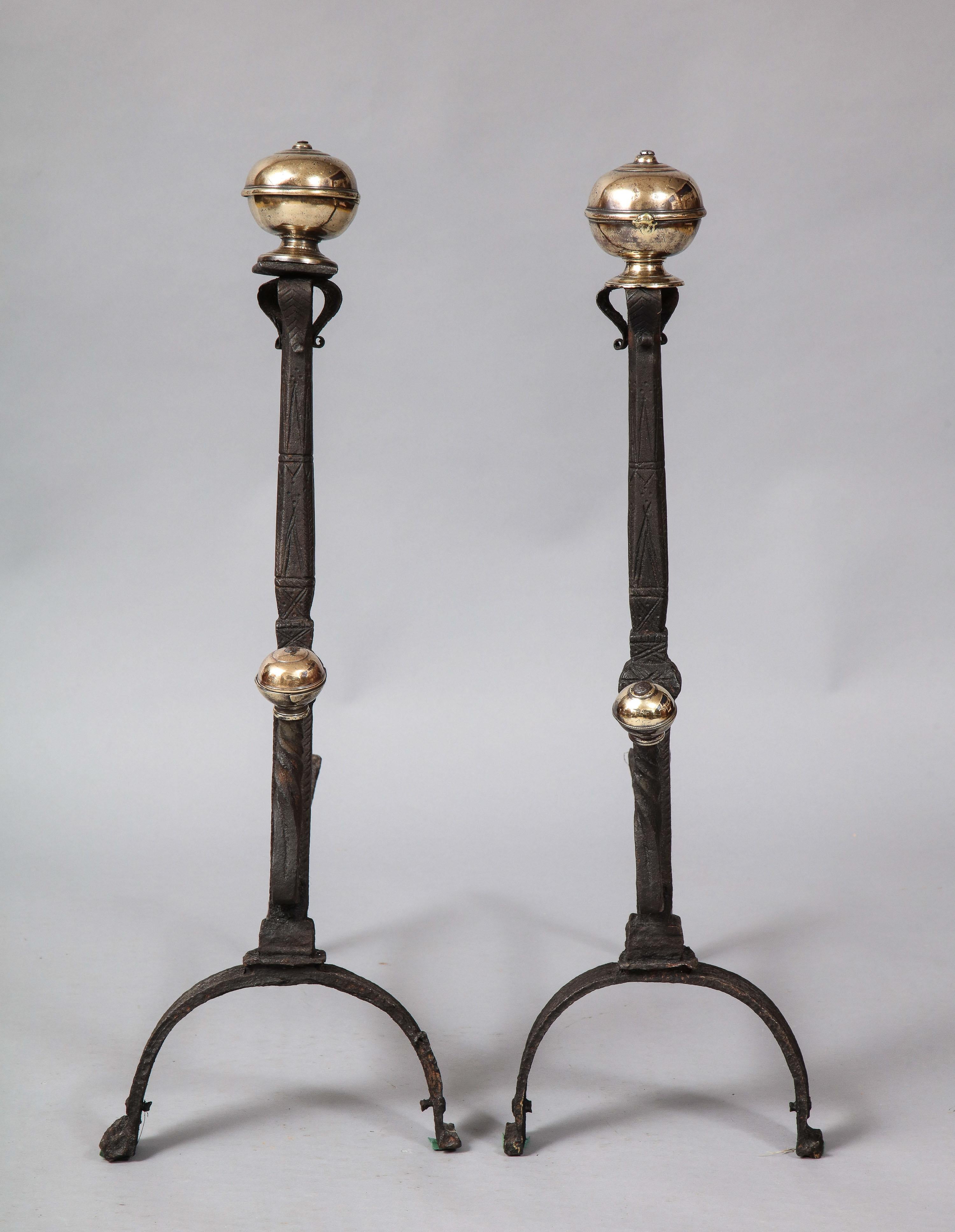 Fine pair of baroque bronze and wrought iron andirons having suppressed ball finials over scrolled petals on octagonal flared shafts both with etched decoration and standing on arched legs with scrolled feet, the fronts with spit supports having