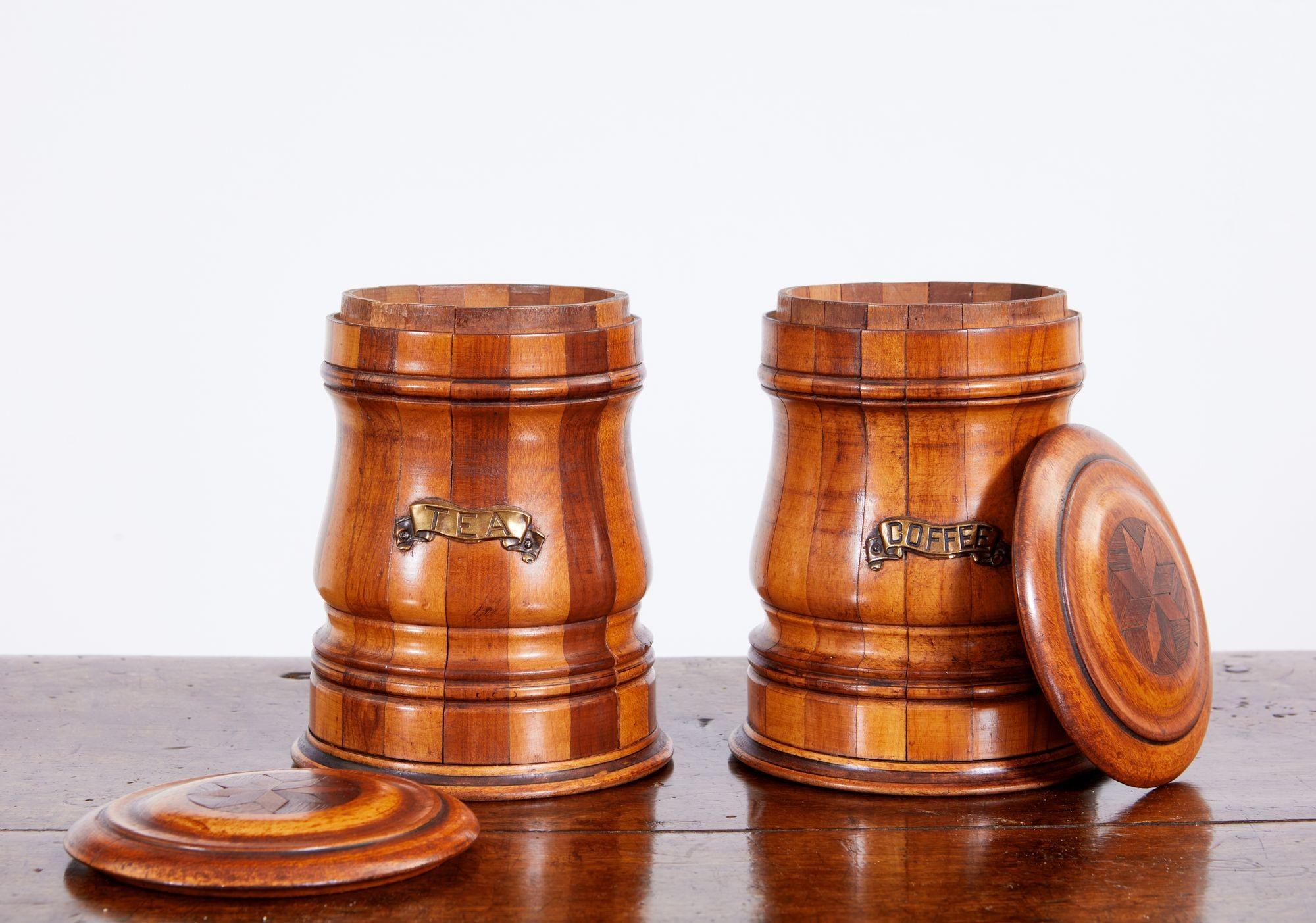 Good pair of late 19th Century English or Scottish mixed wood treen coffee and tea containers, having compass star inlaid turned lids over turned bodies of mixed mahogany and birch staved construction, one labeled 