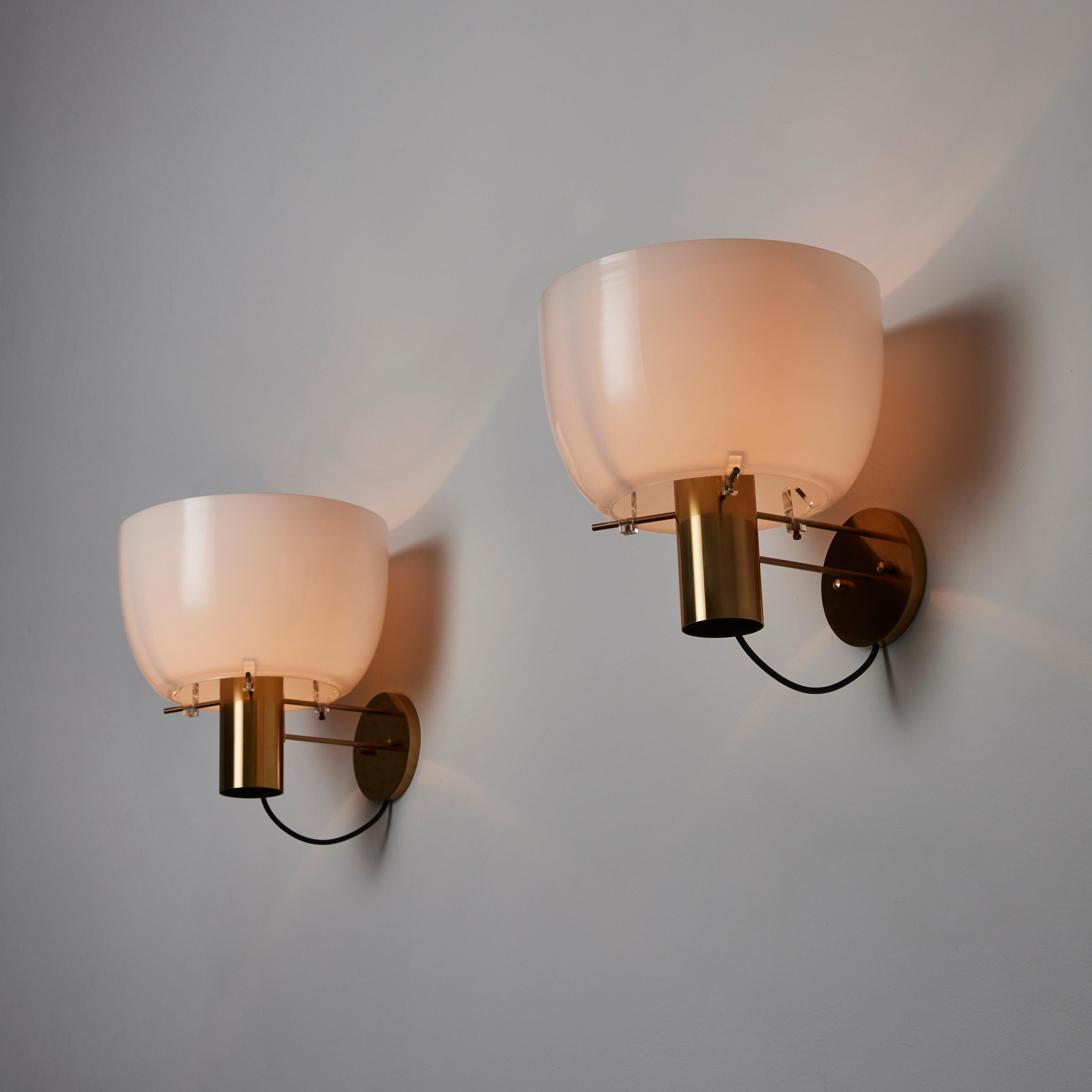 Pair of Model 1121 Sconces by Ostuni & Forti for Oluce. Designed and manufactured in Italy, circa the 1960's. Opaline glass diffusers, orange interior acrylic ring, and lacquered brass armature. Wired for U.S. standards. We recommend a 40w max bulb.