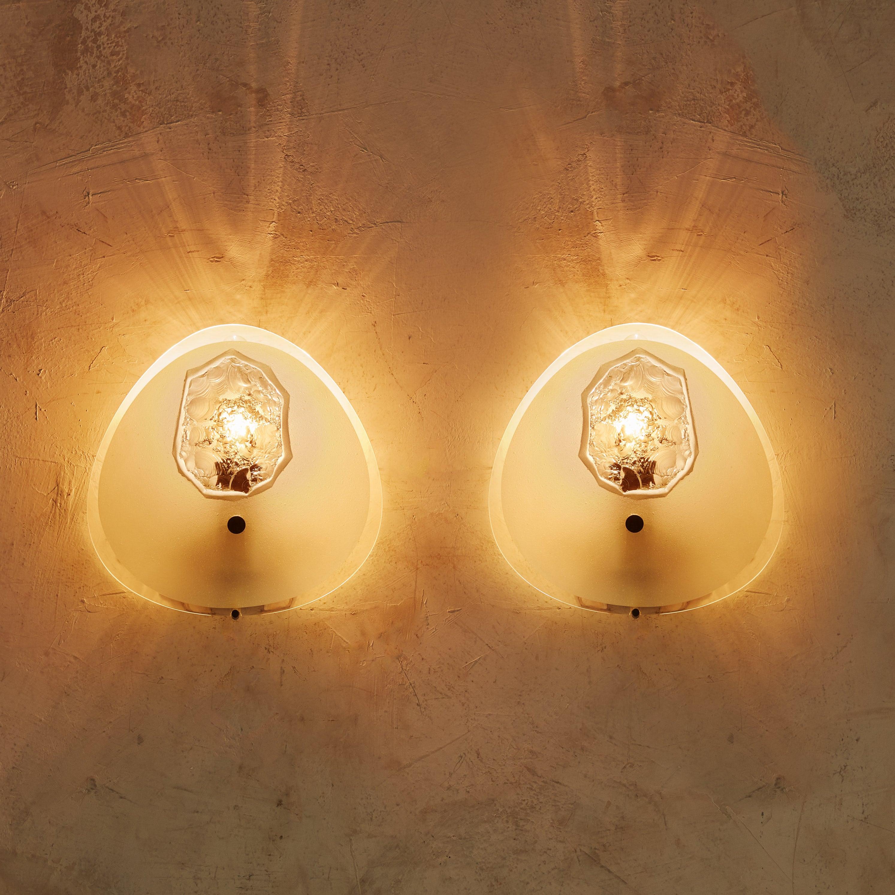 A rare pair of Italian ‘Model 1944’ handblown frosted glass sconces designed by Max Ingrand for Fontana Arte in the 1960s. These stunning oval-form sconces feature irregular beveled edges and chiseled central motifs in a polished finish. When