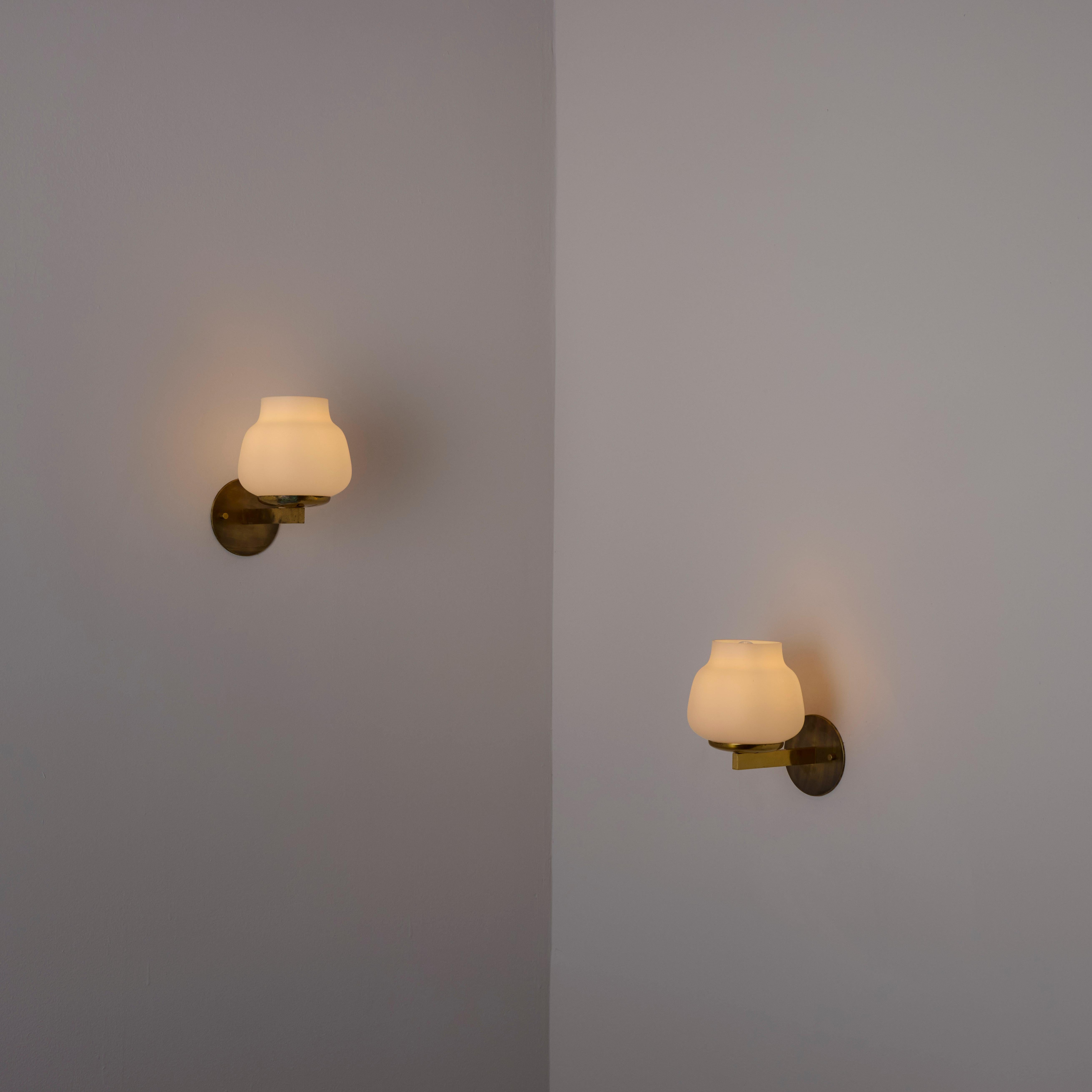 Pair of model 2078 Sconces by Pierre Disderot (Fr, 1950s)

Brass armature with a bulbous opal glass diffuser. The top of the glass offers projection due to a hole cut out. Each sconce holds a single E14 socket-type, adapted for the US. We recommend