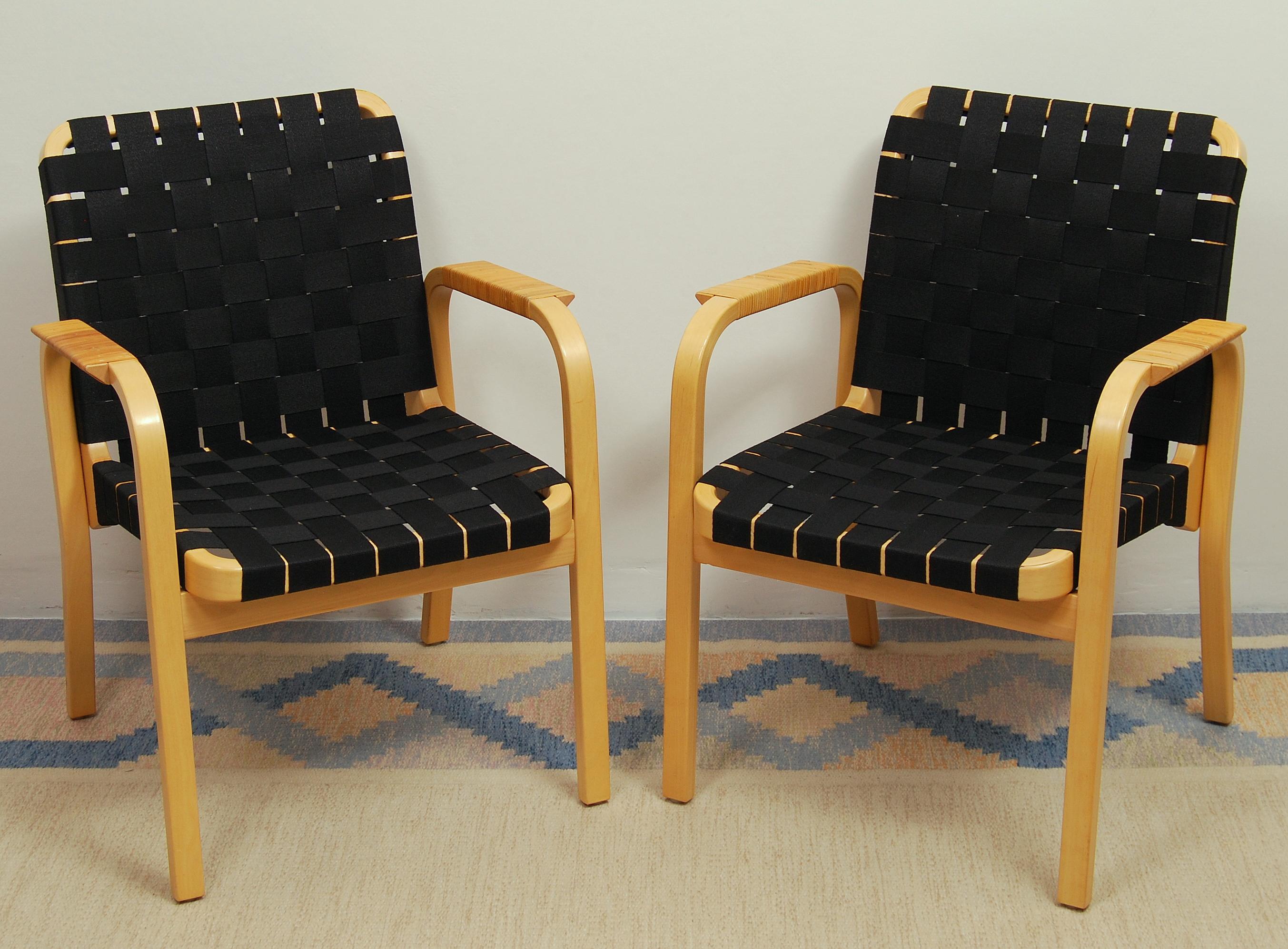 Set of two armchairs model 45 designed by Alvar Aalto in 1947 and made by Artek. This pair of chairs has been reupholstered with new, black linen webbing. The armrests are tightly wound in rattan.
 