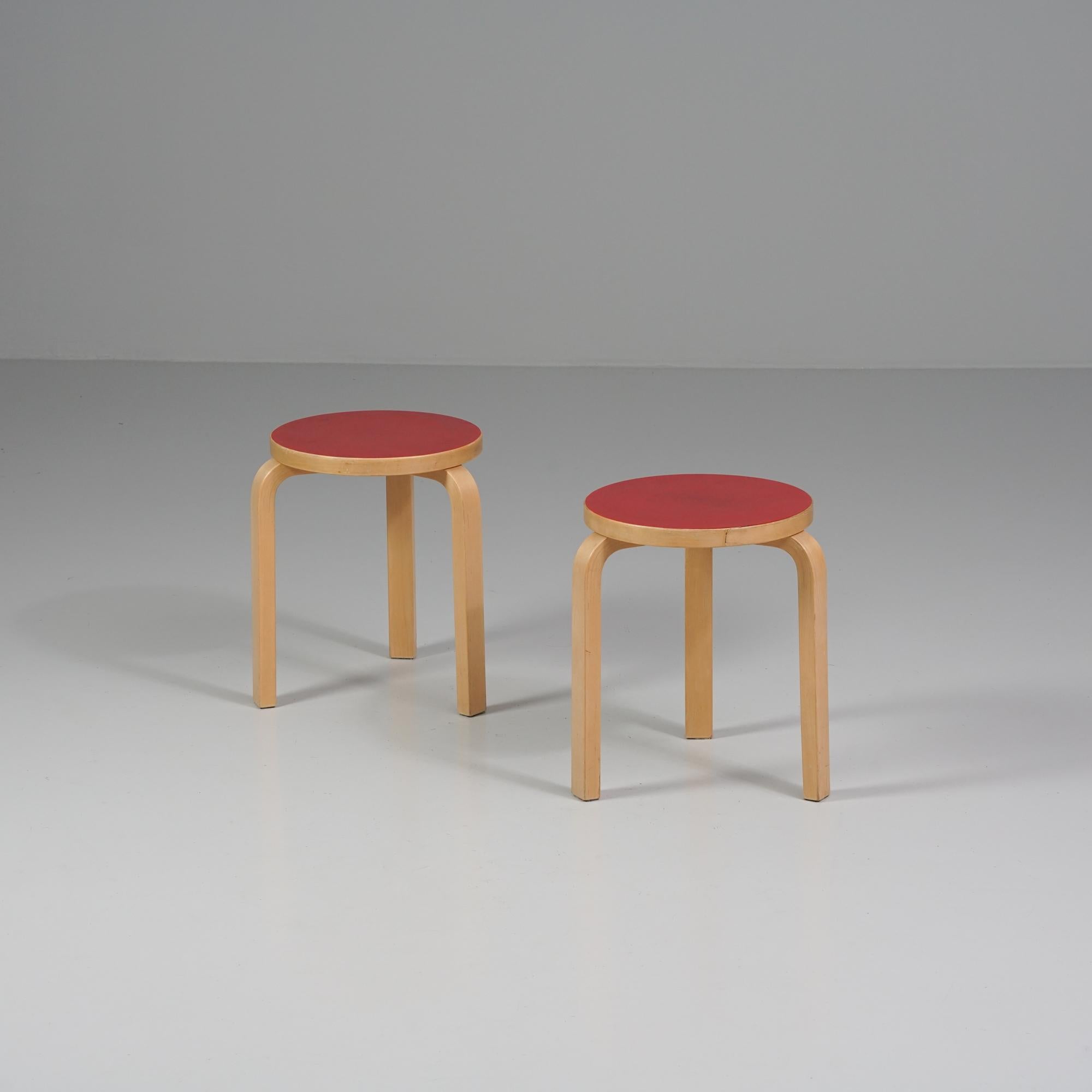 Pair of model 60 stools, designed by Alvar Aalto, manufactured by Artek, 1960s. Birch frame, red linoleum seat. Good vintage condition, patina and wear consistent with age and use. The stools are sold as a set. 

Alvar Aalto (1898-1976) is probably