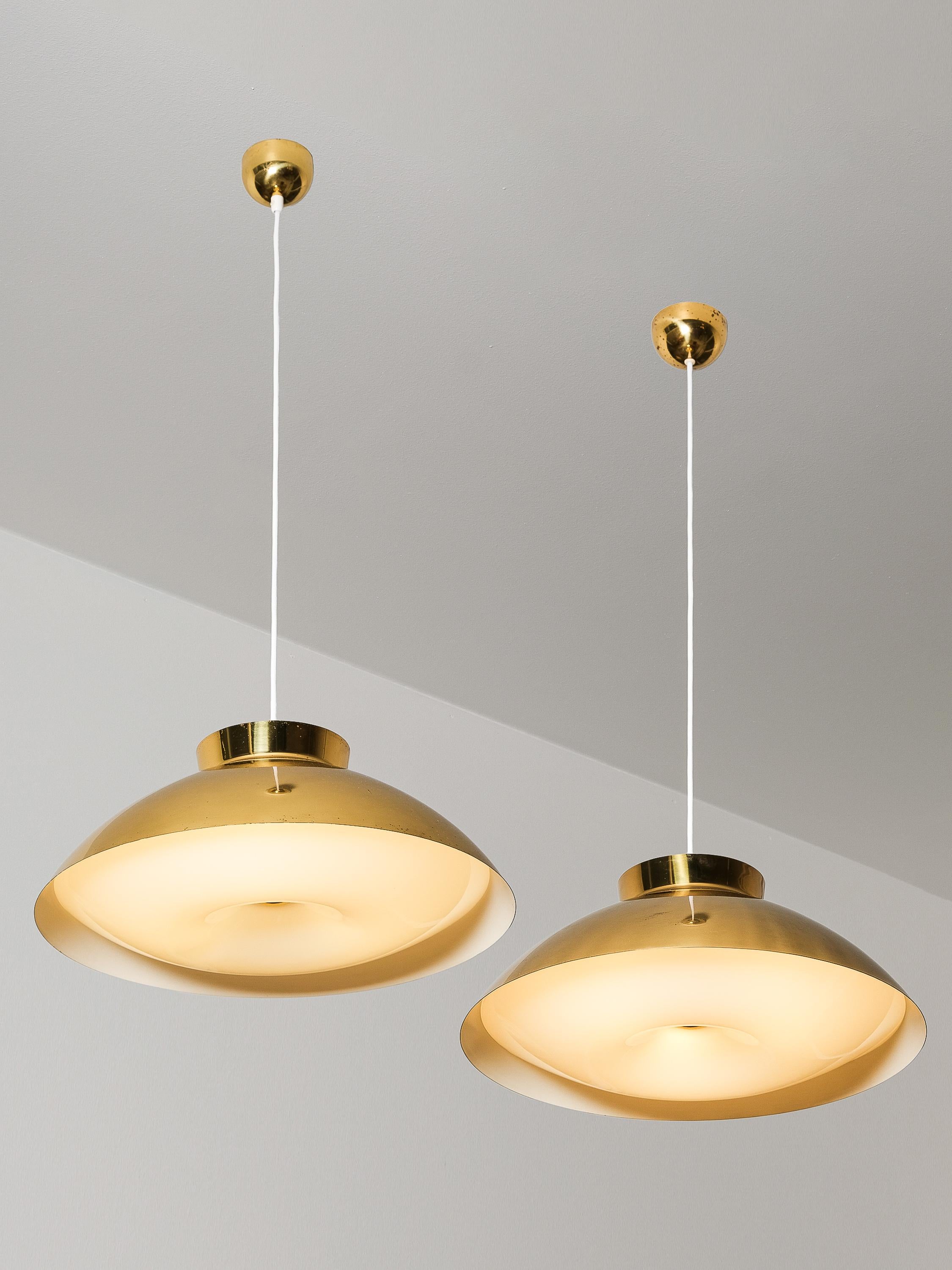 Pair of sizable Mid-Century Modern pendant lights, model 61-368 designed by Lisa Johansson-Pape, and manufactured by Orno in Finland in the 1950s. Full brass shades with an acrylic diffuser at the bottom.

The lamps are in very good original