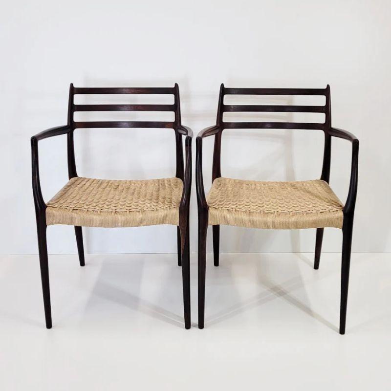 A rarely seen pair of model 62 carver armchairs, designed in 1966 by Niels Møller for J.L. Møller Møbelfabrik in Denmark. The frames are made from solid rosewood that have been refinished and the seats have been woven in new Danish paper cord in our