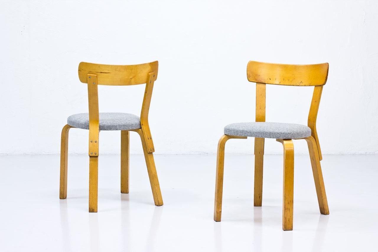 Pair of “Model 69? chairs designed by Alvar Aalto. Manufactured by Artek factory in Hedemora, Sweden. The Swedish production of Artek was running in between 1946 and 1956. Chairs are made from lacquered birch wood with seats reupholstered with