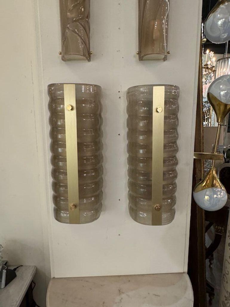 Elegante pareja de apliques de cristal de Murano translúcido estriado con detalles de latón. ¡Hace una hermosa declaración!
18,5h x 7,5w x 4d
