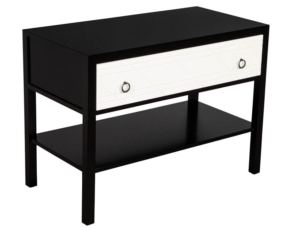 Pair of modern black and white nightstands. Finished in contrasting tones with unique geometric façade. Each table features one drawer with pull ring hardware. Bottom tier shelf perfect for books and curiosities.

Price includes complimentary curb