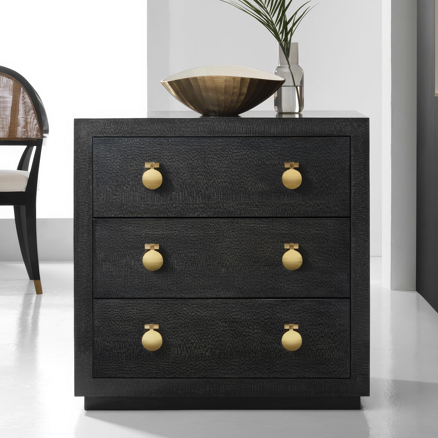 With polished brass hardware showcases the distinctive texture of black lacewood veneer that is enhanced by a deep ebony finish. The streamlined design features three drawers, each adorned with contemporary brass pulls that provide an elegant