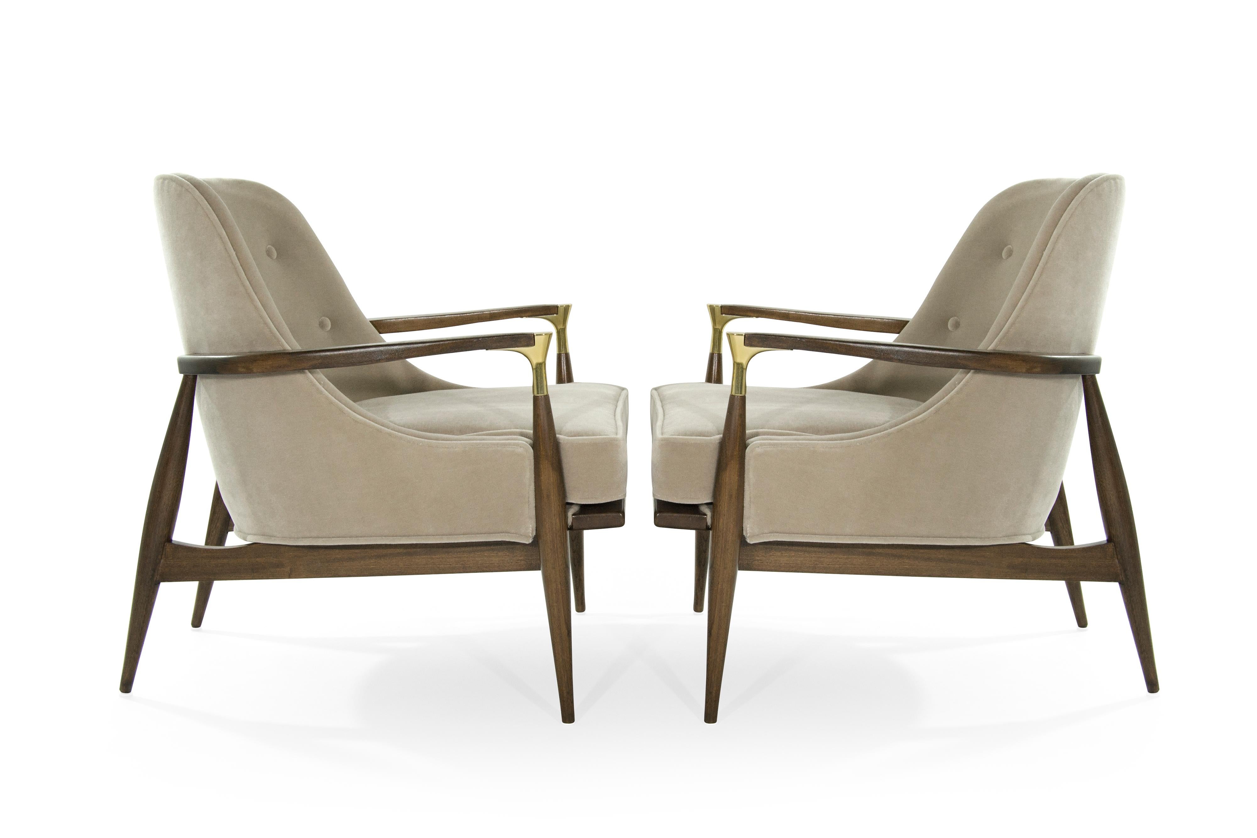 Rare lounge pair of chairs in the style of Ib Kofod-Larsen. Featuring brass details on arms. Newly upholstered in natural mohair. Sculptural walnut frames completely restored.