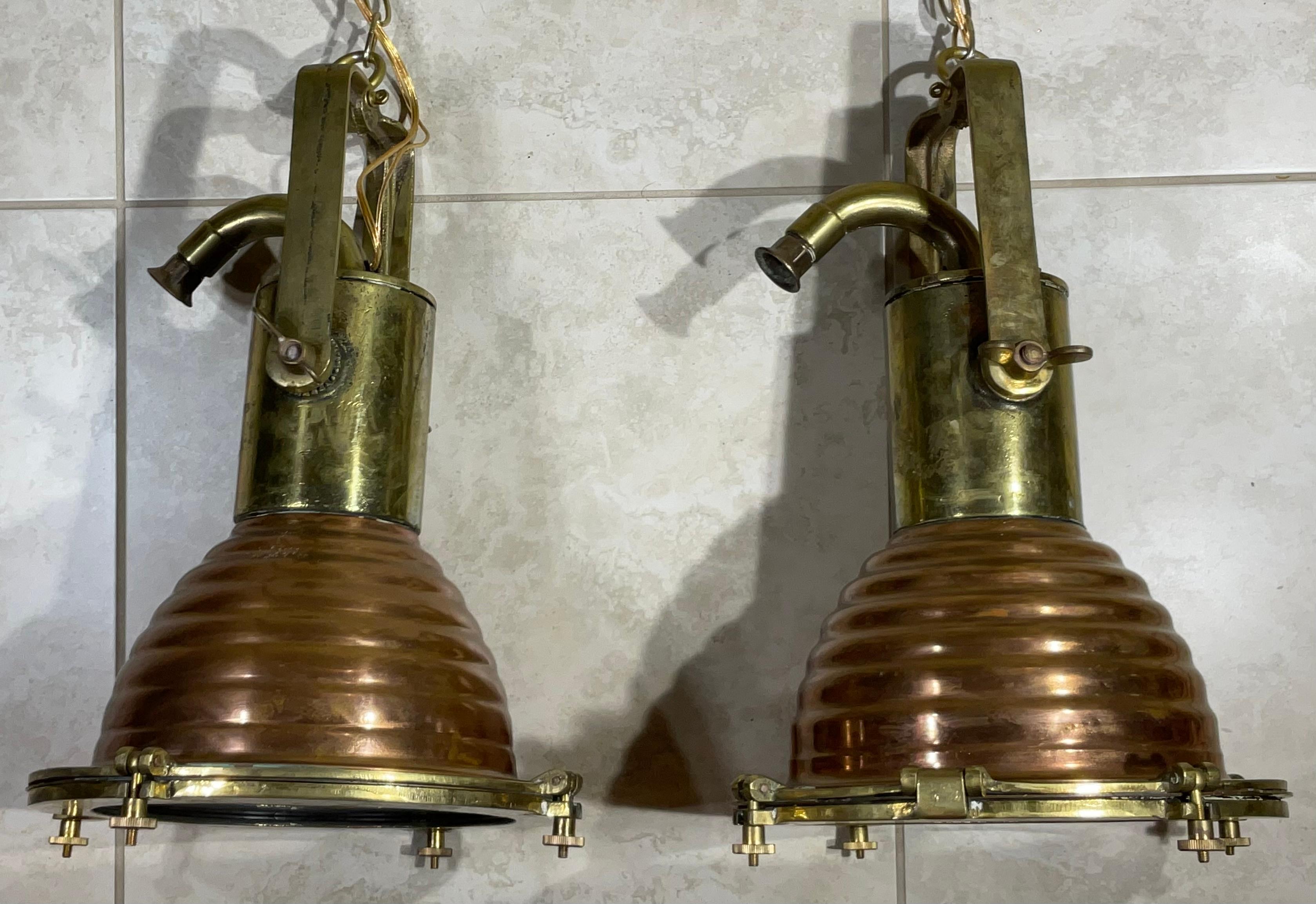 Pair of stylish light fixture pendants made of hand crafted solid brass and solid copper come with all the original brass canopies and chain intact. They are in a good / used condition and the beautifully patinated two tone brass and copper shades .
