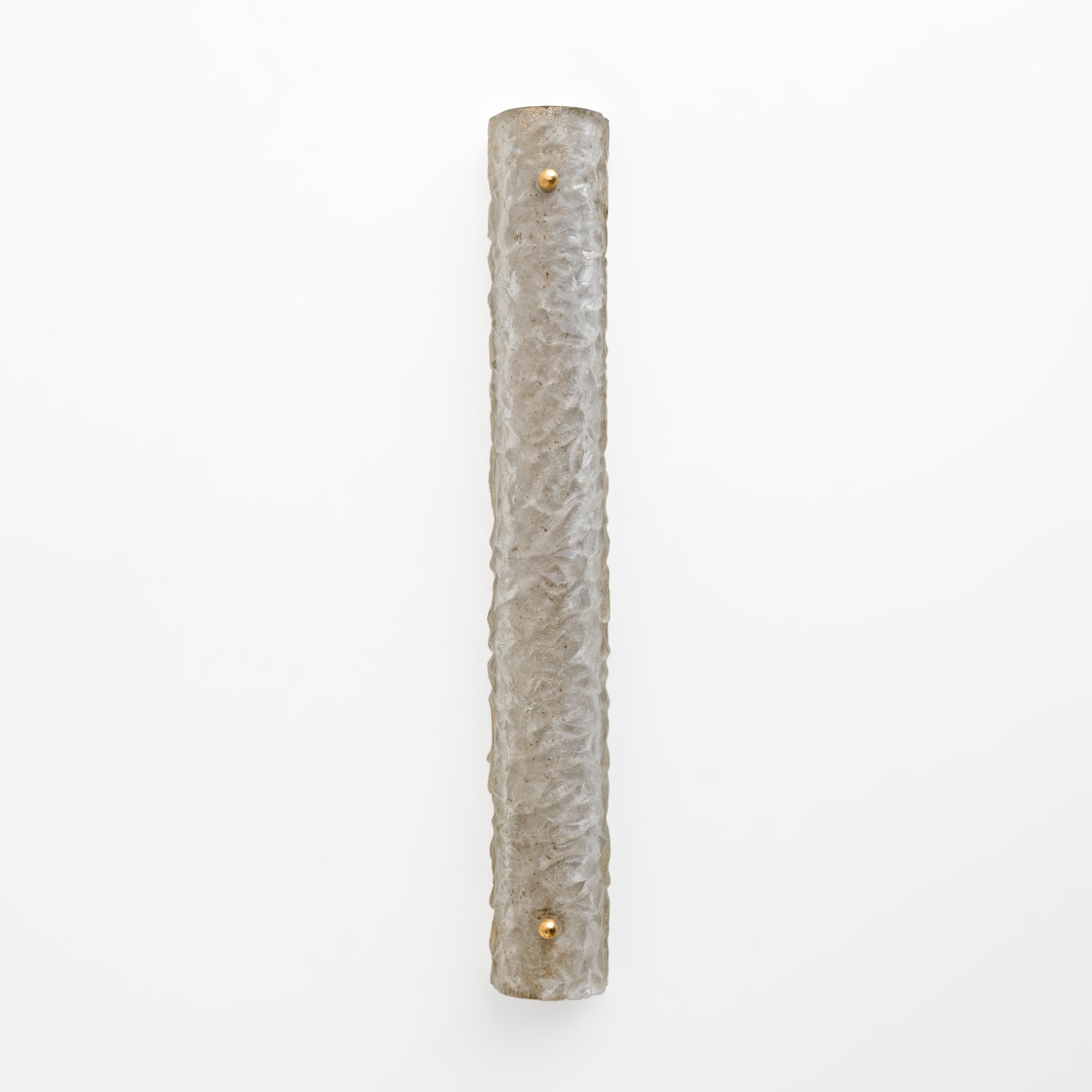 Estos apliques son de cristal de Murano texturado con efecto scavo, un tipo de cristal ornamental con una superficie rugosa y opaca en el interior y un acabado que imita el cristal antiguo, predominantemente gris. La estructura de soporte es de