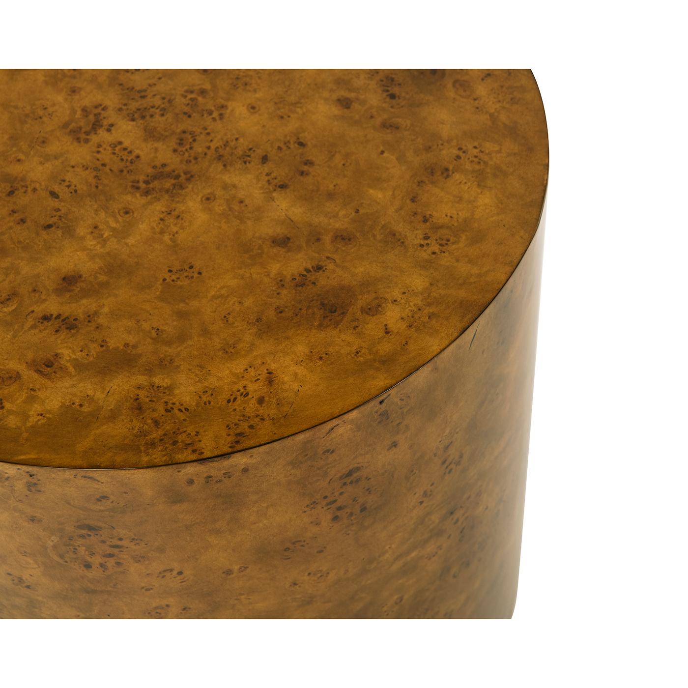 A sleek and sophisticated accent piece that blends natural textures with contemporary elegance. Featuring a richly patterned mappa burl veneer, this table showcases a warm, organic aesthetic. 

The cylindrical silhouette is complemented by a
