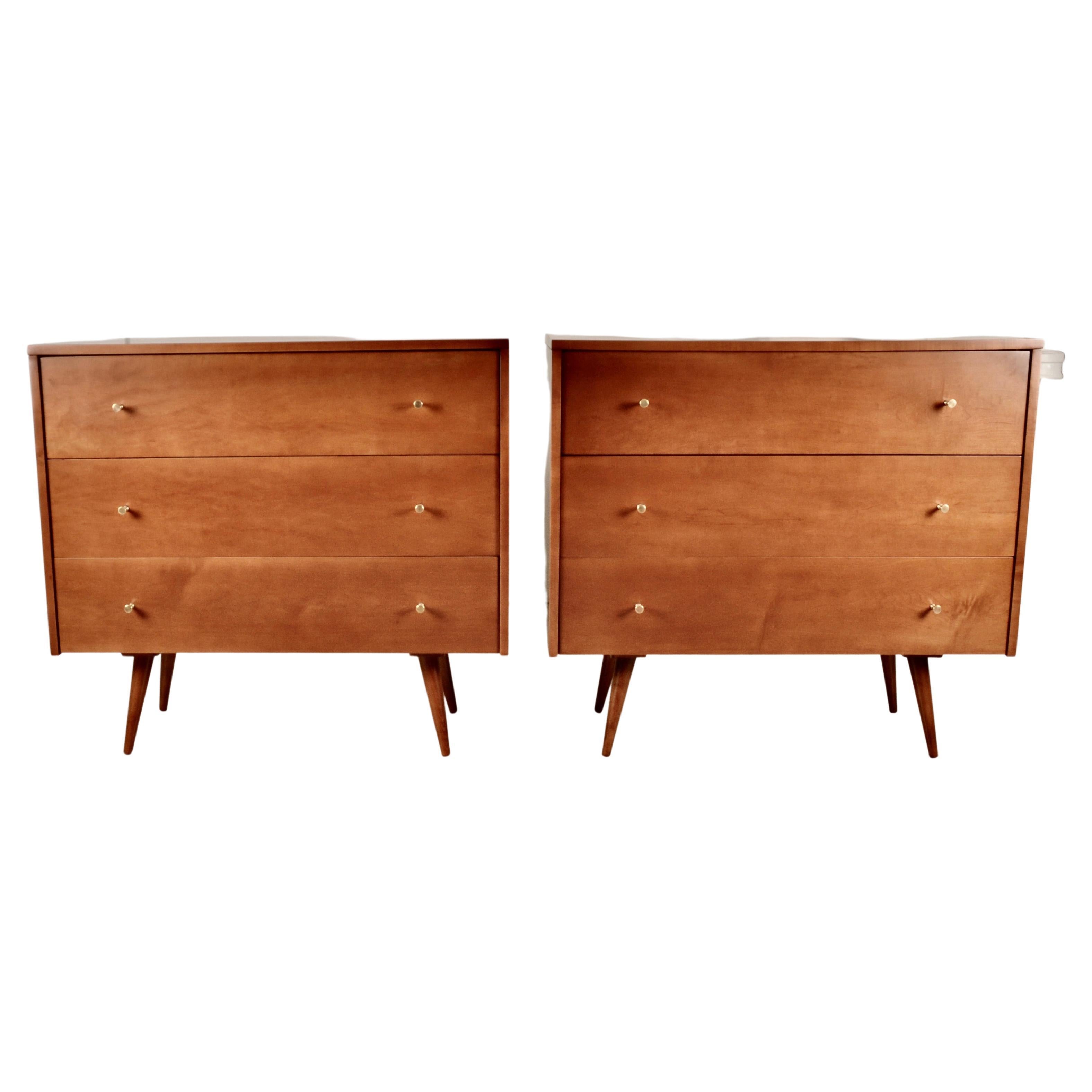 An iconic pair of McCobb chests, manufacturers by Planner Group circa 1950s. Distinctive modern legs. Original solid brass custom pulls. This pair has been fully refinished in a satin lacquer finish. Very fine restored condition.