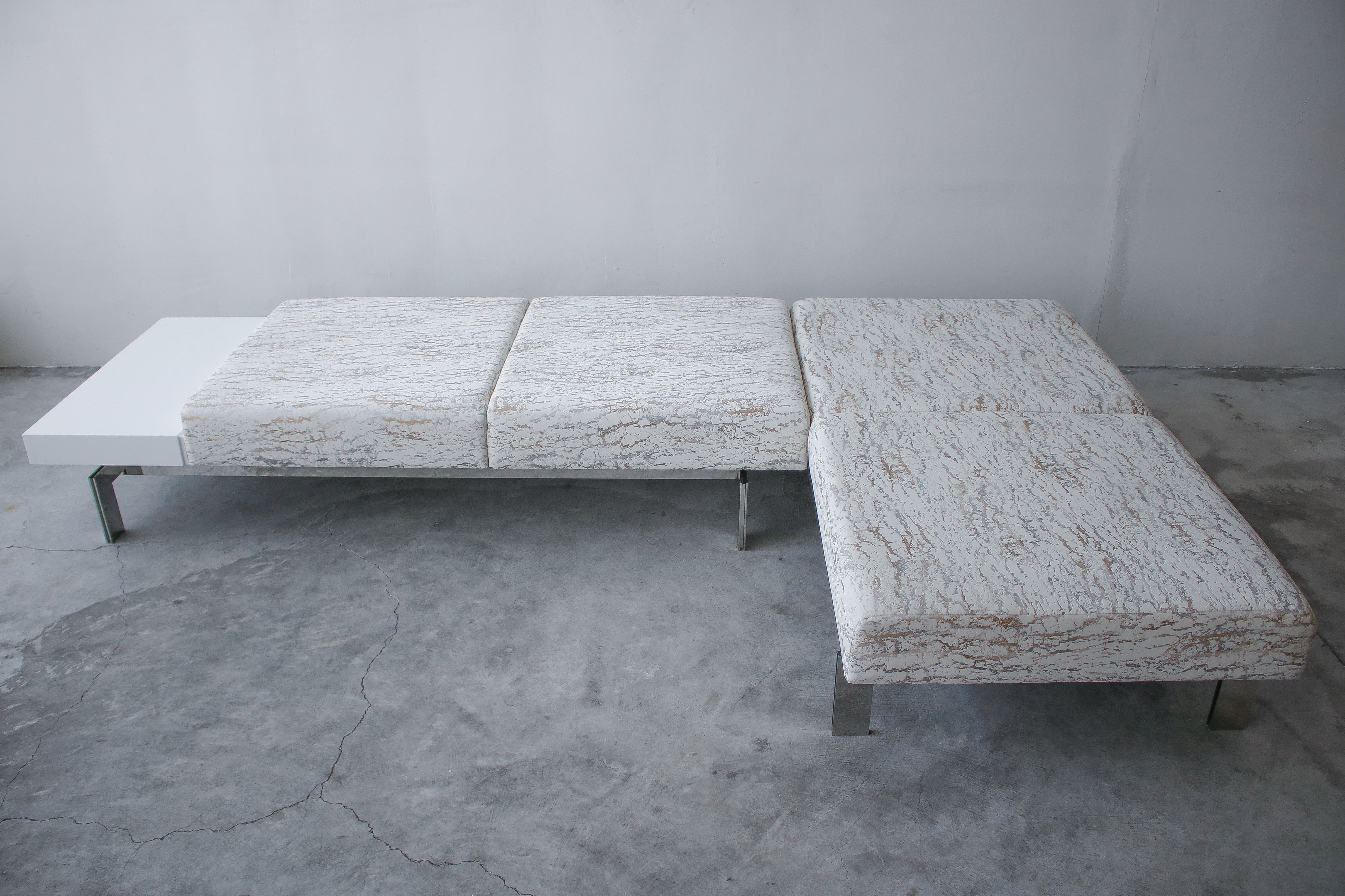 Precioso y sustancioso par de bancos de acero inoxidable espejado, con armazón flotante, uno de ellos con una mesa adosada de laminado blanco sin juntas. Los sofás están increíblemente bien hechos, y pesan fácilmente más de 150 libras cada uno. Por