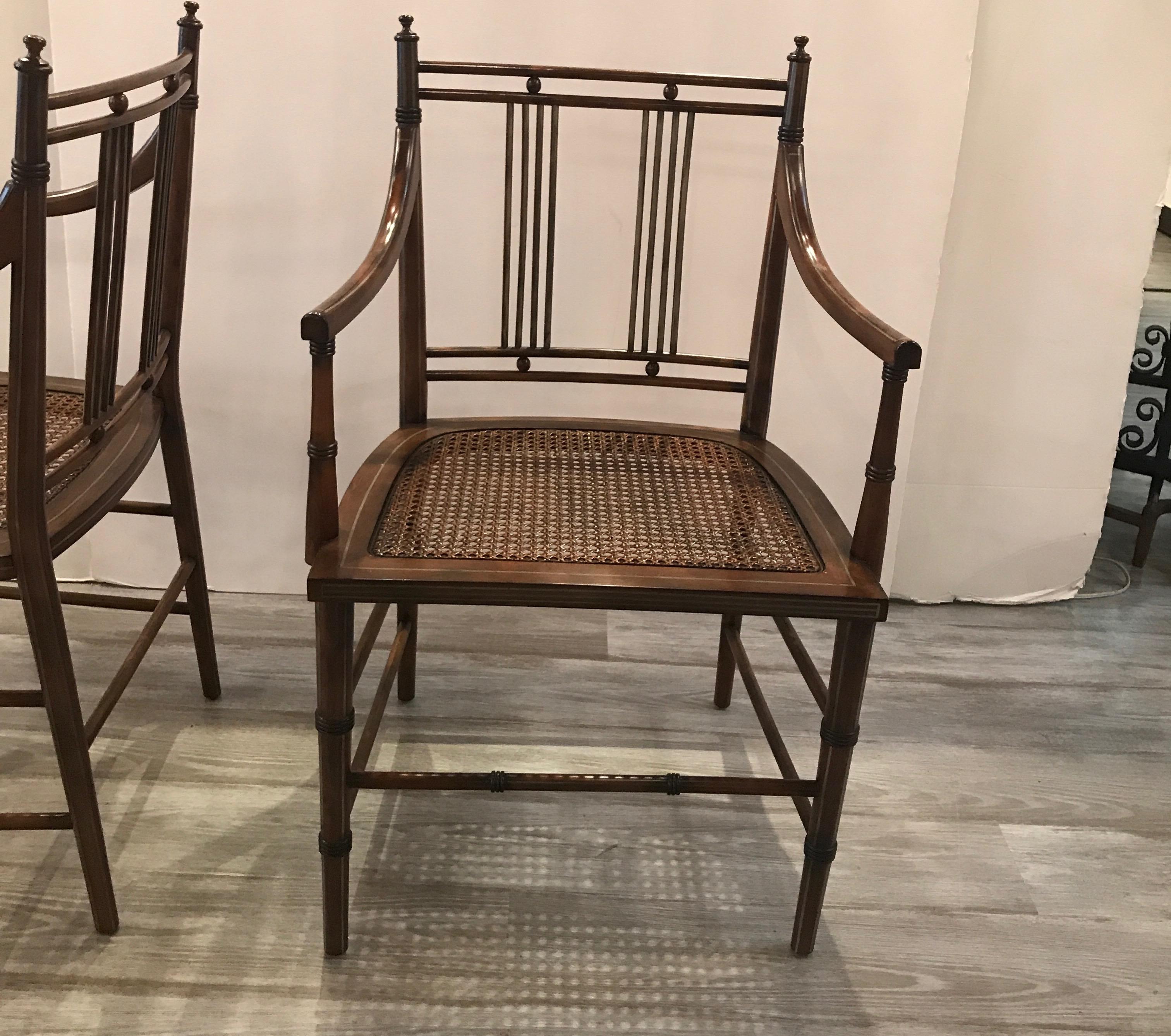 Chic pair of fruitwood armchairs with caned seats. The chairs are thin pewter pinstripe on some of the rungs and along the sides. These chairs have a Bauhaus inspired design. These are price for the pair, with a total of 4 chairs. (2 pairs).