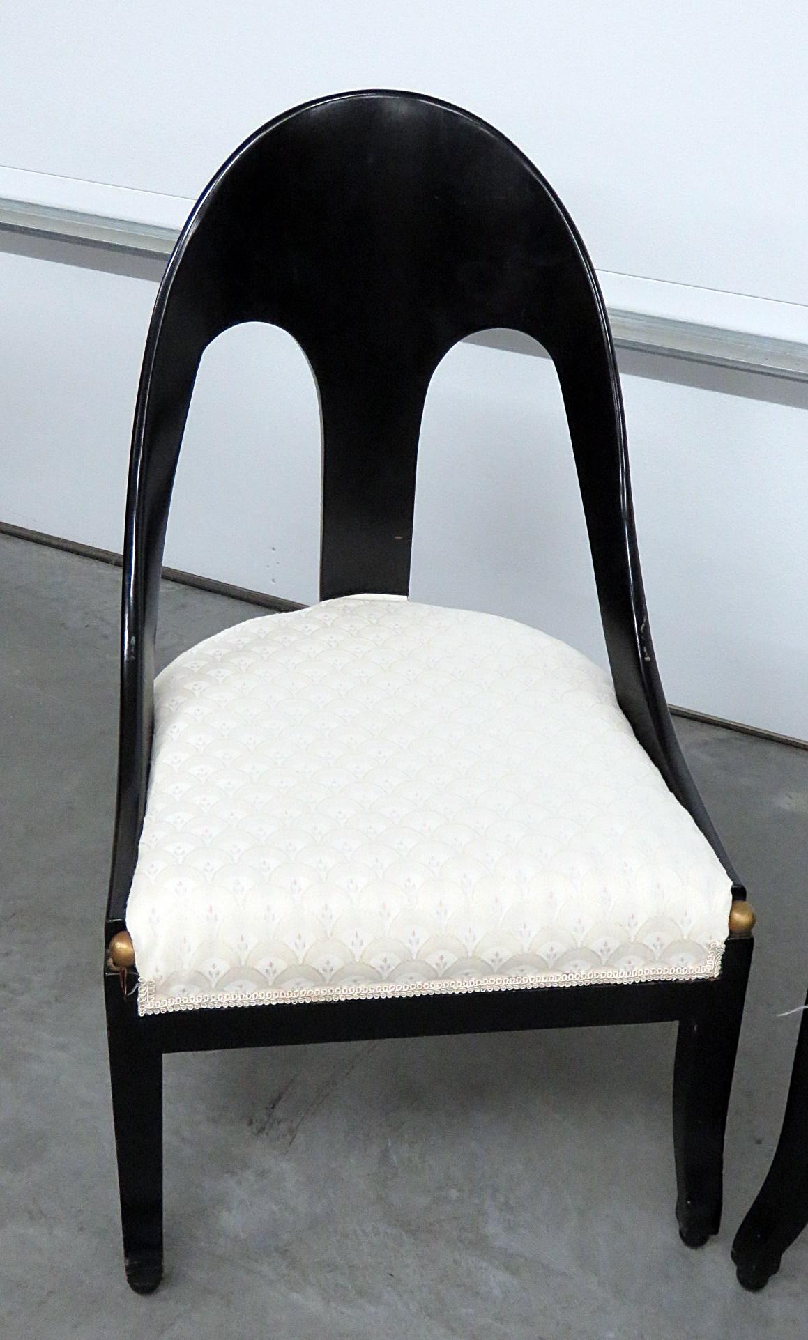Pair of modern design ebonized club chairs with cream upholstery and gilt accents.