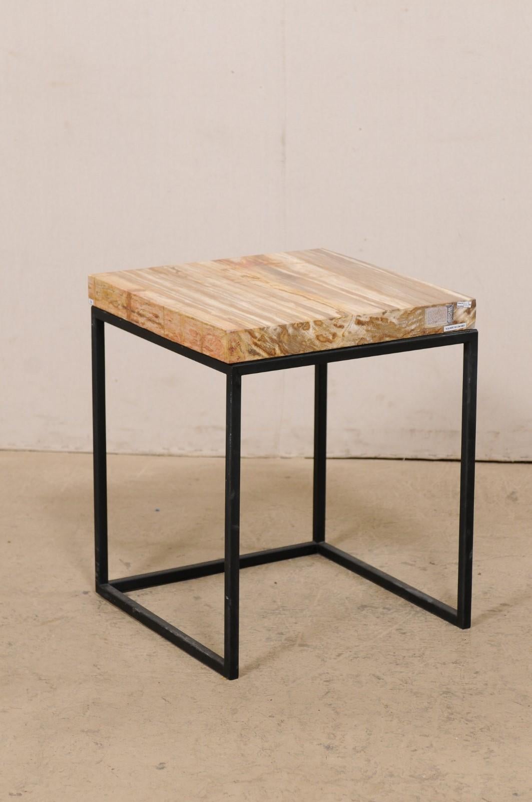 A pair of modern style custom petrified wood top side tables. This pair of tables each feature a square-shaped petrified wood top, in beautiful warm brown and beige tones. The tops are supported by a custom metal base, which is black in color, with