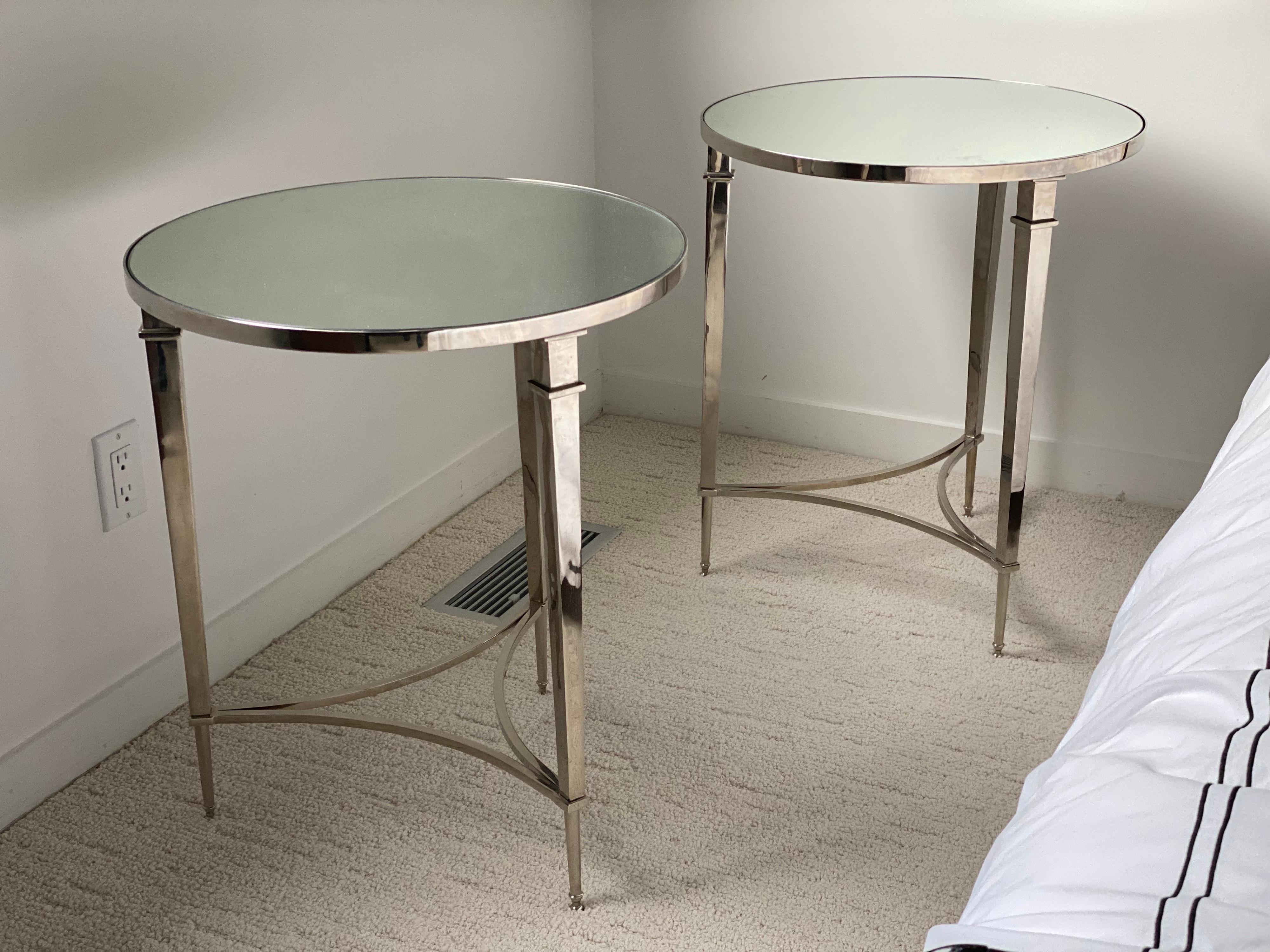 Pair of Modern Directoire style round Nickel end tables with mirror tops.
Three classic, straight tapered legs connected by elegant curved supports and inset mirrored top. These are great looking and classic. They could be paired with antiques or