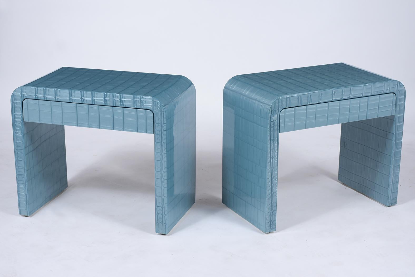 A fabulous pair of vintage modern nightstands handcrafted out of wood finely covered with a faux alligator laminate veneer and is fully restored. This pair of sleek design side tables feature a unique blue color U-shape and a single drawer that
