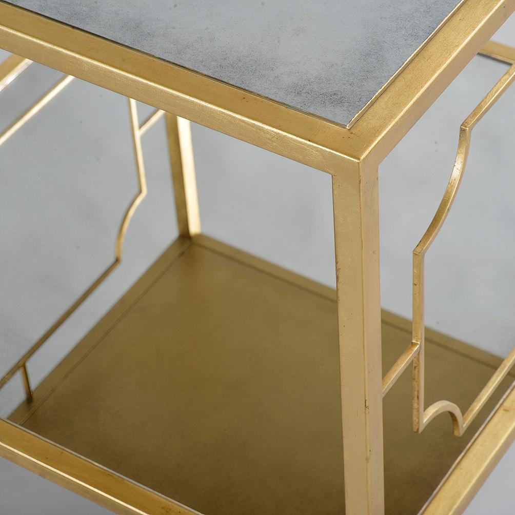 Modern gilt square side table with antique mirror top and shelf, straight legs, and portrait frame detail on the table sides, has a 