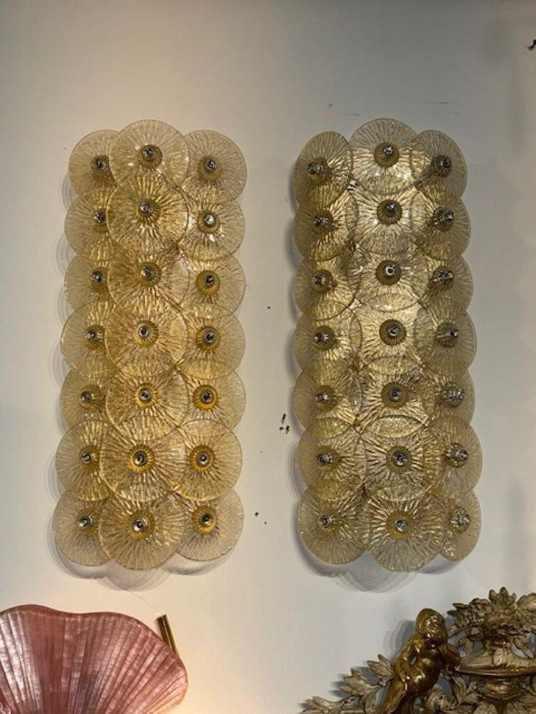 This pair of modern Gold Disc Mazzega Manner Sconces features a striking design. The sconces exude a modern style, adding a touch of elegance to any space. Perfect for adding a touch of glamour to any room, these sconces would be a beautiful