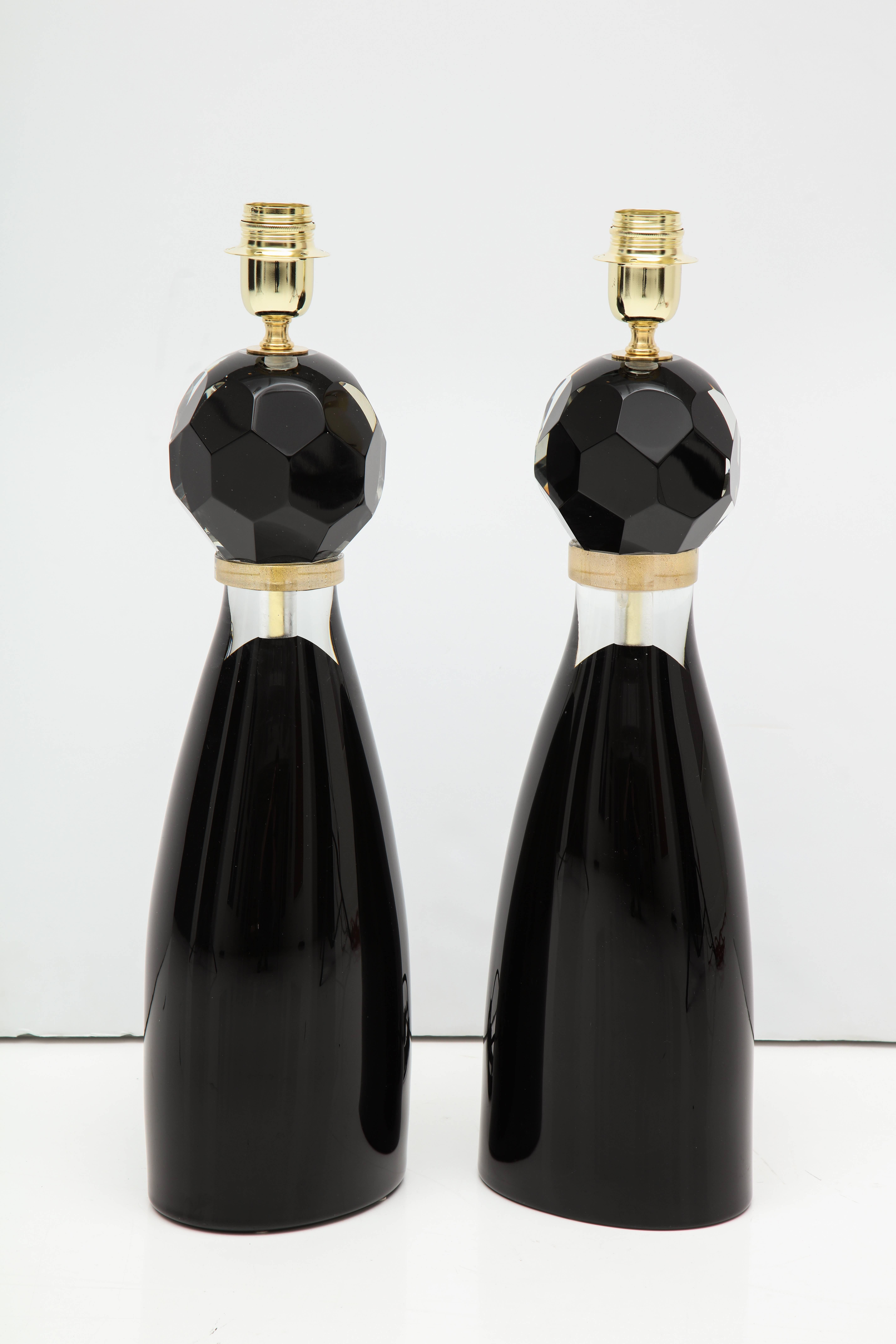Paar italienische mundgeblasene Murano-Glas-Tischlampen, bestehend aus einer facettierten schwarzen Glaskugel auf einem modernen schwarzen und klaren Sockel. Ein goldener Glasring trennt die beiden Glaselemente. Signiert von Glasermeister Alberto