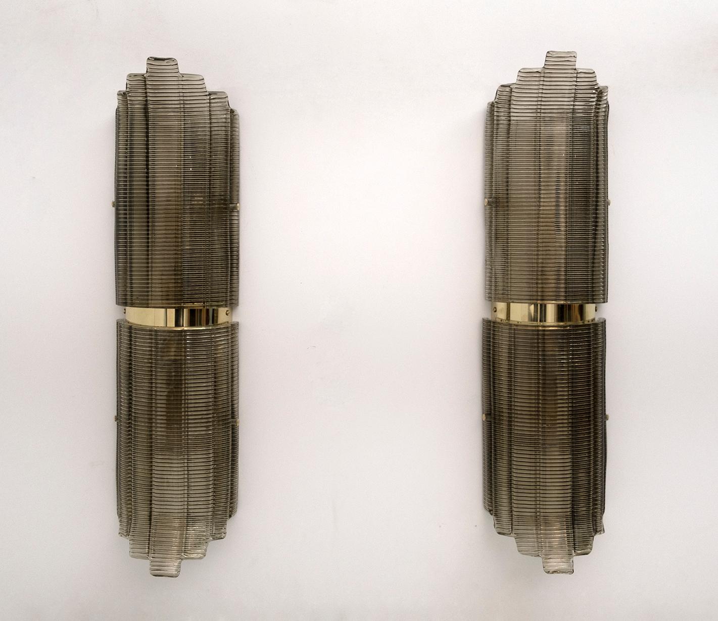 Pair of smoke-colored Murano glass wall lamps in structured glass and brass. The glass is textured with ribs and is curved in design, creating a superb decorative impact. Each wall light requires a medium base bulb and is wired to match US standards.