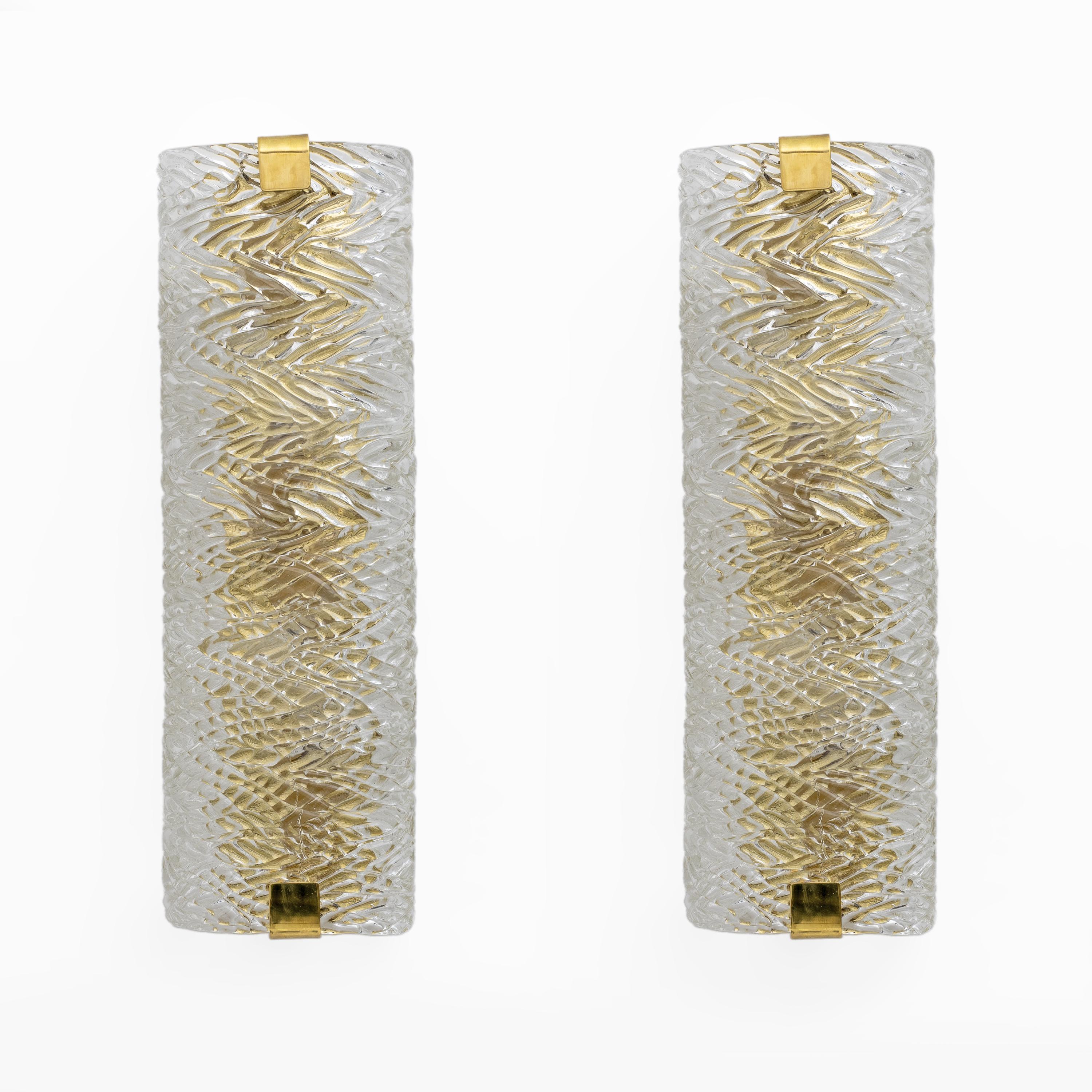 Coppia di applique in vetro di Murano trasparente con texture che ricorda quasi la corteccia degli alberi. Ogni lampada è composta da un unico vetro curvo, sostenuto da due piastre di ottone. Sono di alta qualità ed emanano una piacevole luce calda.