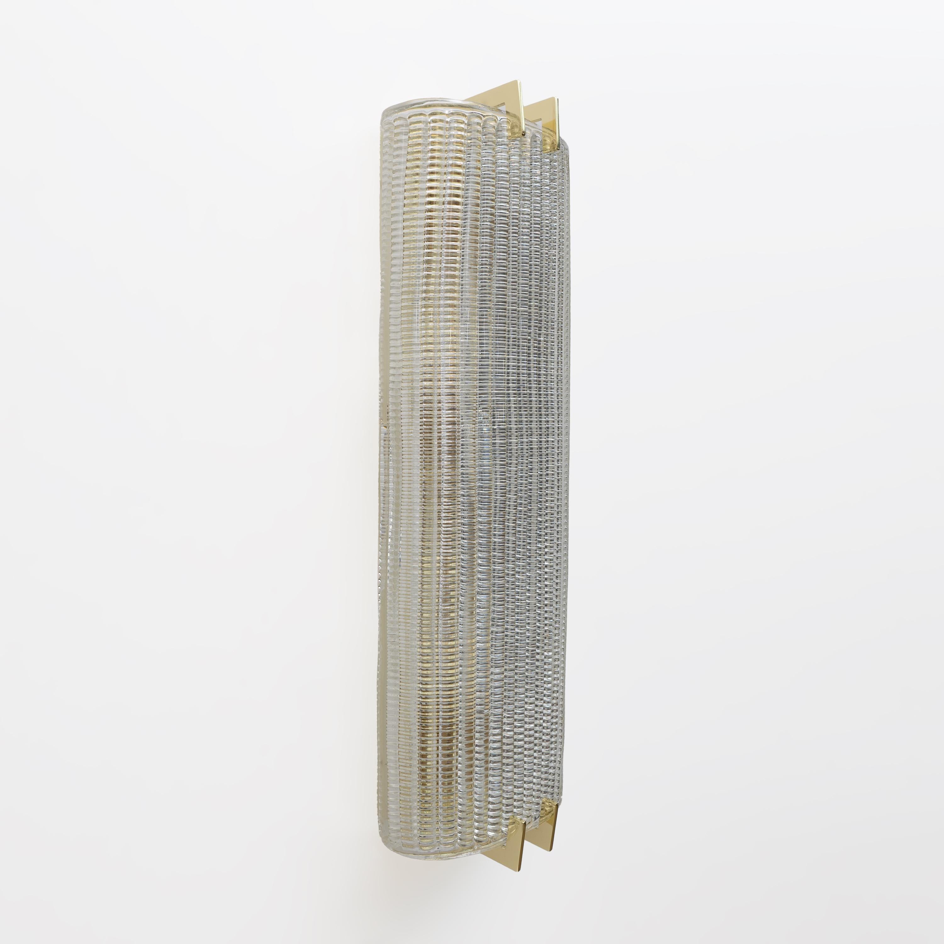 Ein Paar Wandleuchter aus strukturiertem, klarem Muranoglas. Das Glas ist geriffelt und gewölbt, was eine großartige Wirkung in einer Glasscheibe im Stil des Art déco erzeugt. Die tragende Struktur besteht aus reinem, vergoldetem Messing. Jede