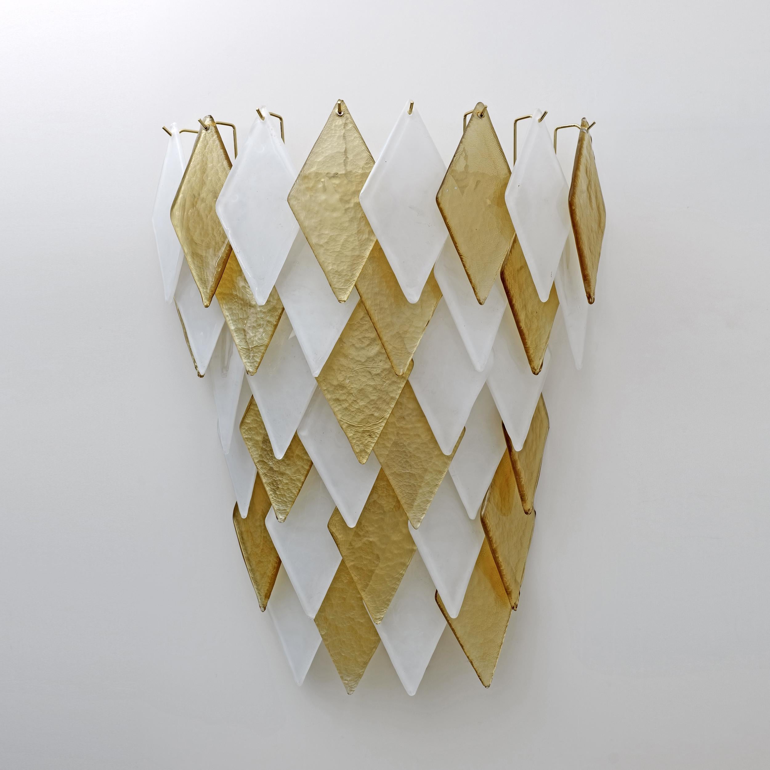 Pair of wall lamps, each composed of 35 gold and white Murano blown glass rhombuses. The lamps have six E14 lamp holders for Europe, on request we can mount adapters for bulbs with E12 socket for the USA. The structure is in brass and gold metal.