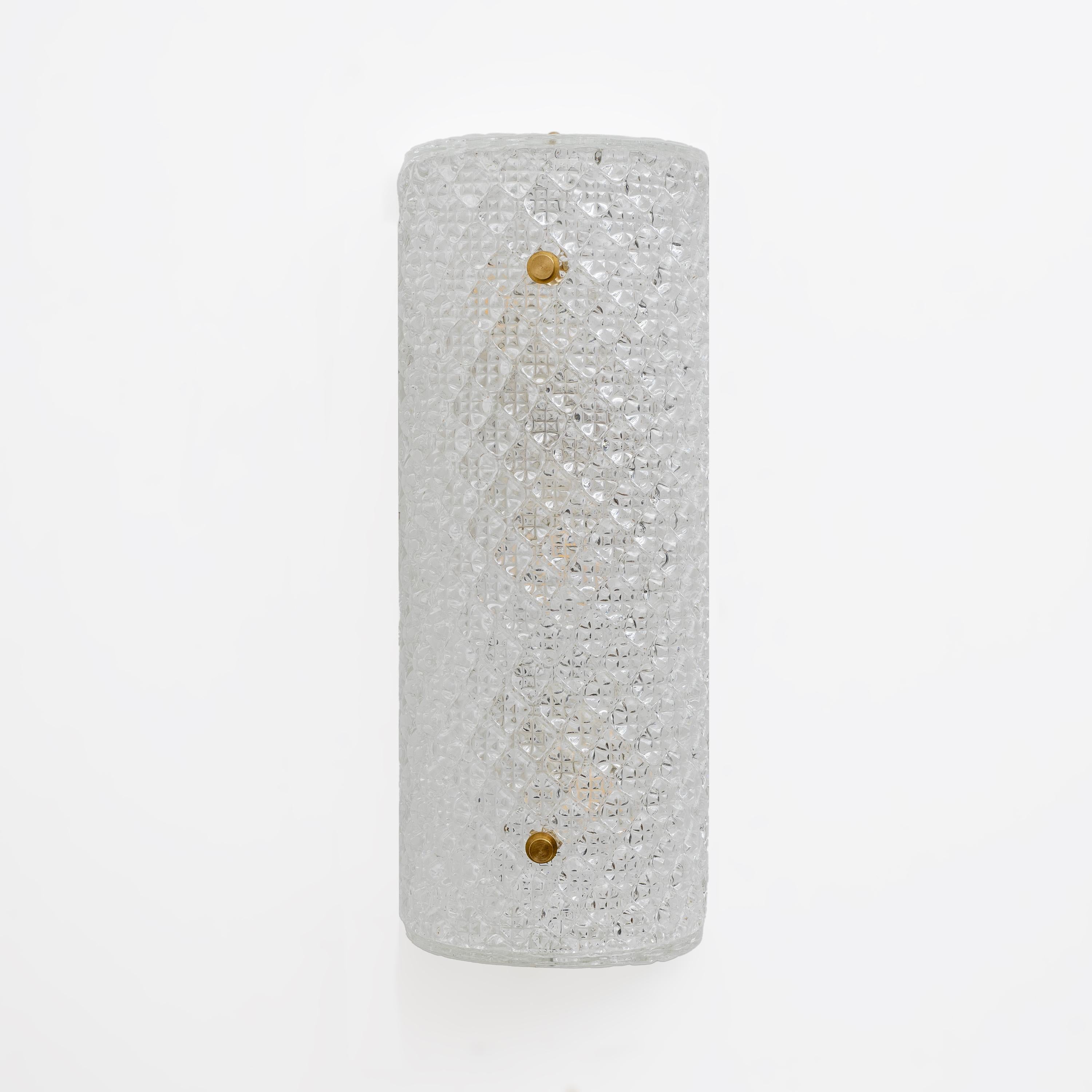 Pair of elegant luxury wall sconces. The sconce features a cylindrical design and a textured surface with intricate diamond-shaped decorations, crafted from clear crystal Murano glass, creating a sparkling and sophisticated look. Each glass is